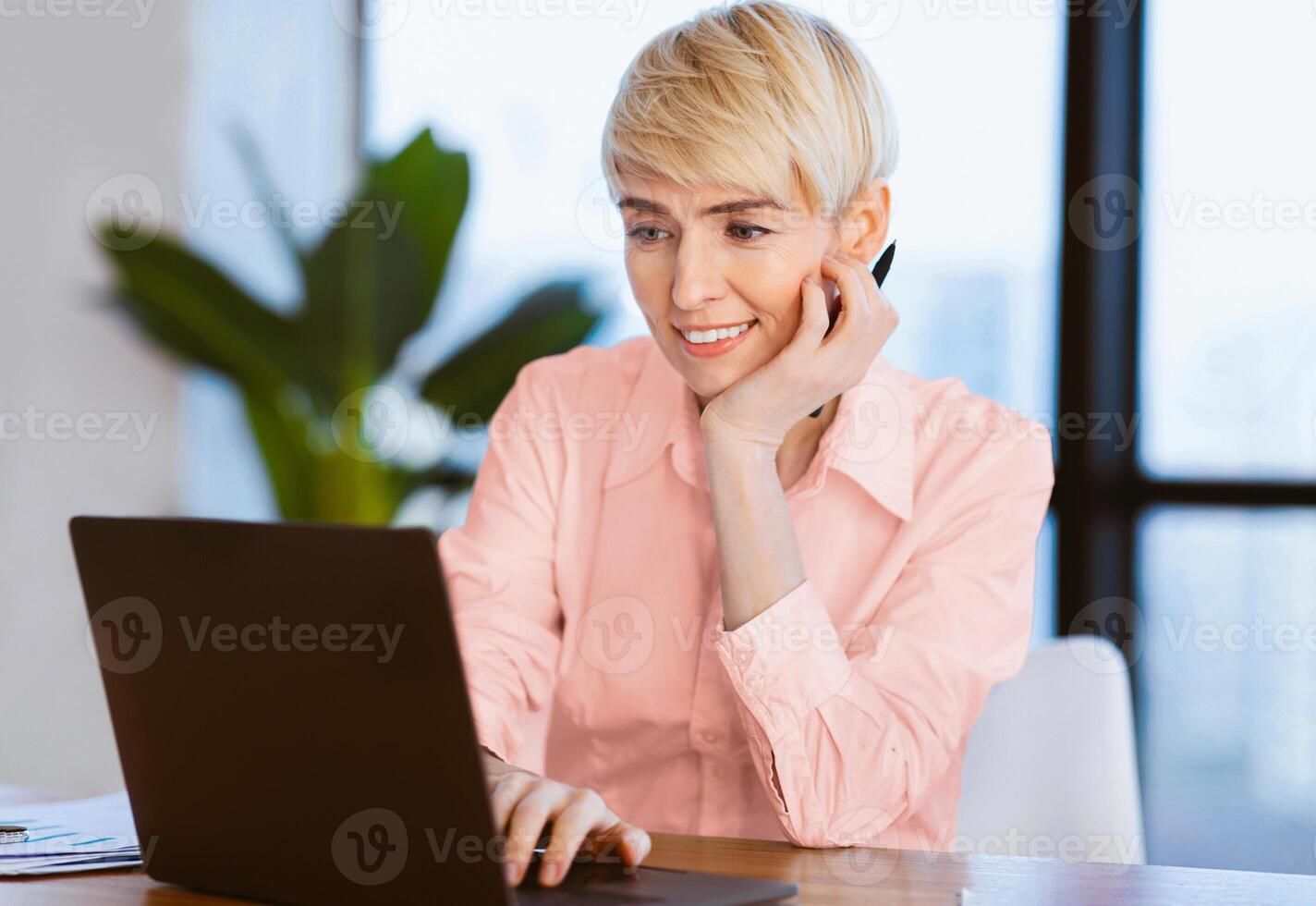 Smiling Mature Woman At Laptop Browsing Internet Working At Workplace In Modern Office. Computer Work. Selective Focus photo