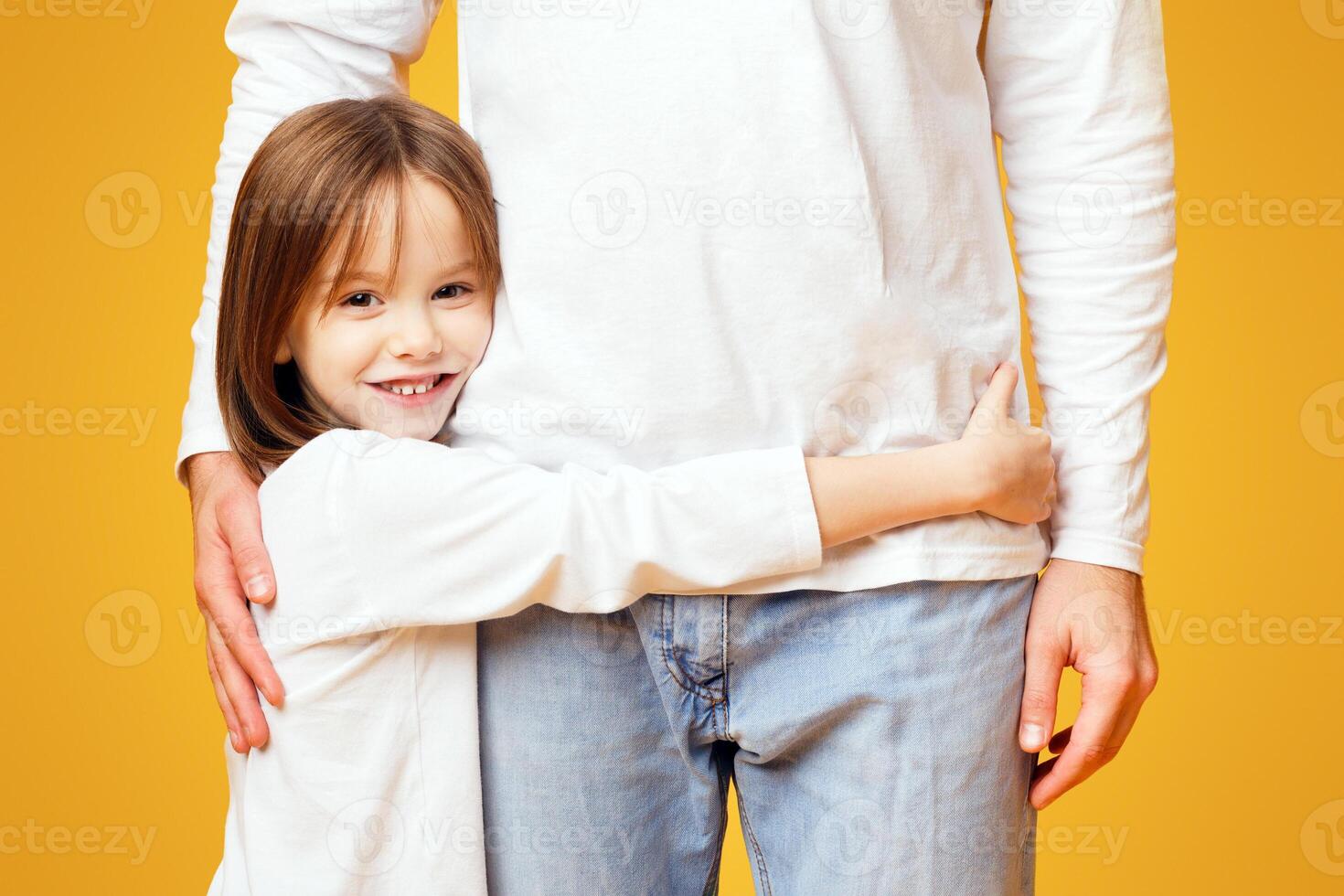 I love you dad. Close up of cute smiling little girl hugging her dad over yellow background photo