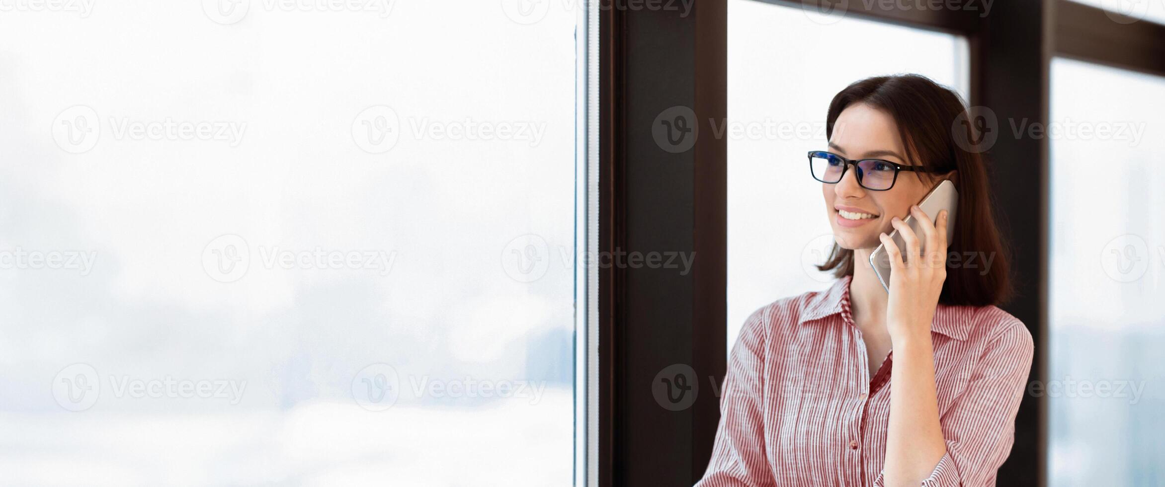 Communication, Technology And Success Concept. Young woman talking on phone near window at office workplace, copy space photo