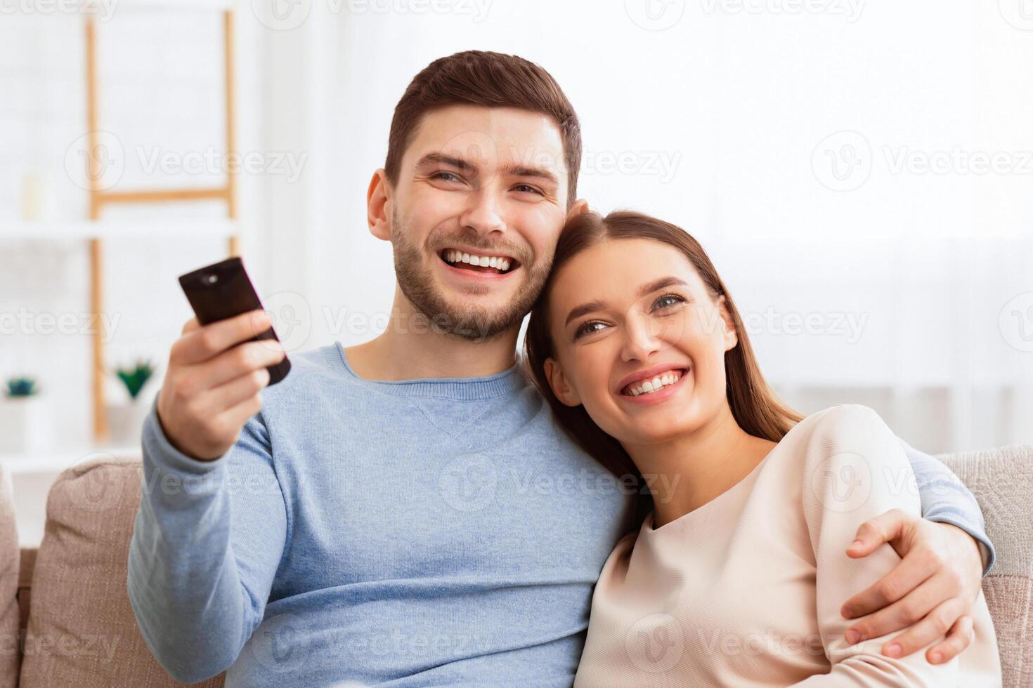 Weekend. Happy Couple Watching TV Relaxing Sitting On Sofa At Home. Selective Focus, Copy Space photo
