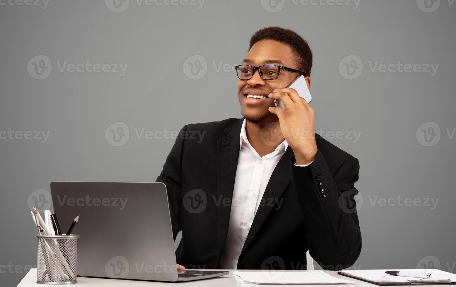 Smiling Afro Businessman Talking On Cell Phone, Discussing Details With Client, Working On Laptop. Copy space photo
