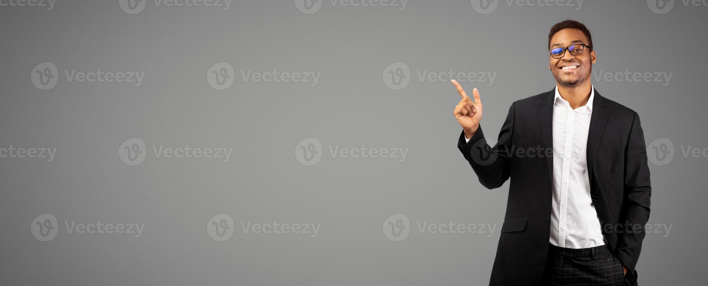 Best Choice. Smiling black businessman pointing at blank space, looking at camera. Panorama, place for text or promo photo