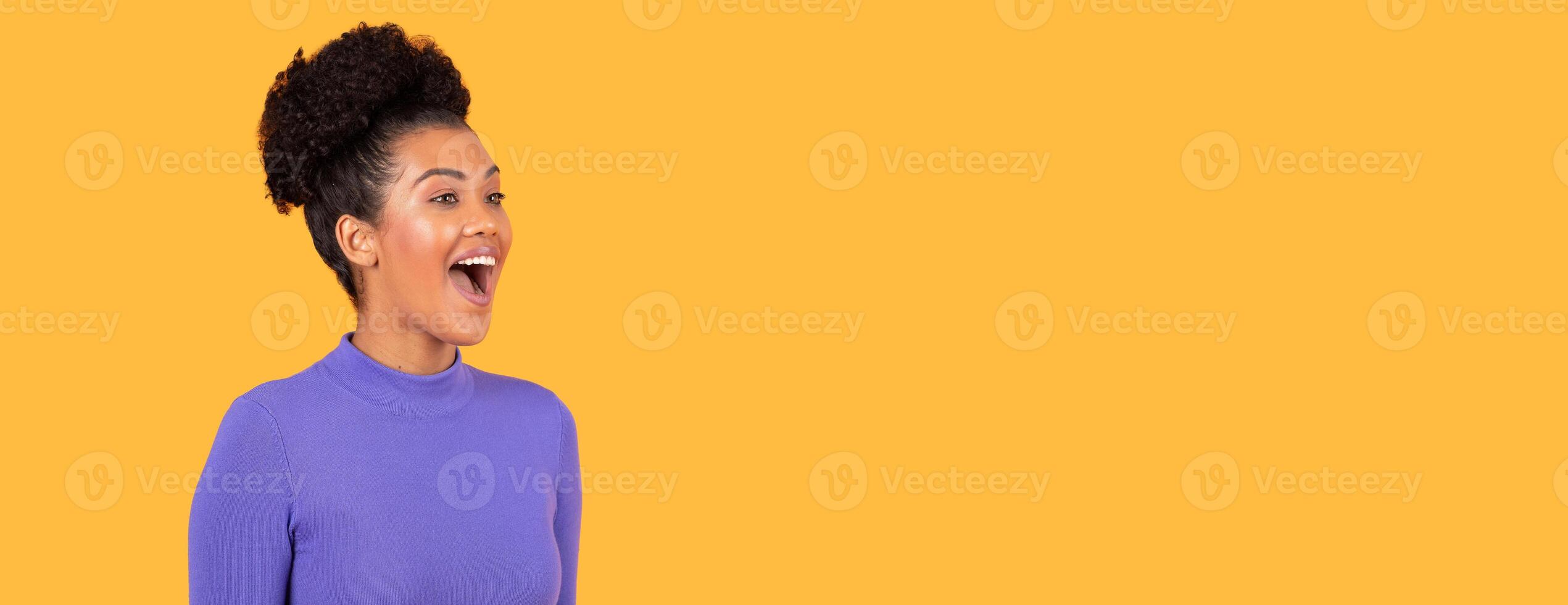 A woman with curly hair smiles widely and expresses joy in a vibrant orange background. Her purple top contrasts beautifully, highlighting her cheerful demeanor and animated expression, copy space photo