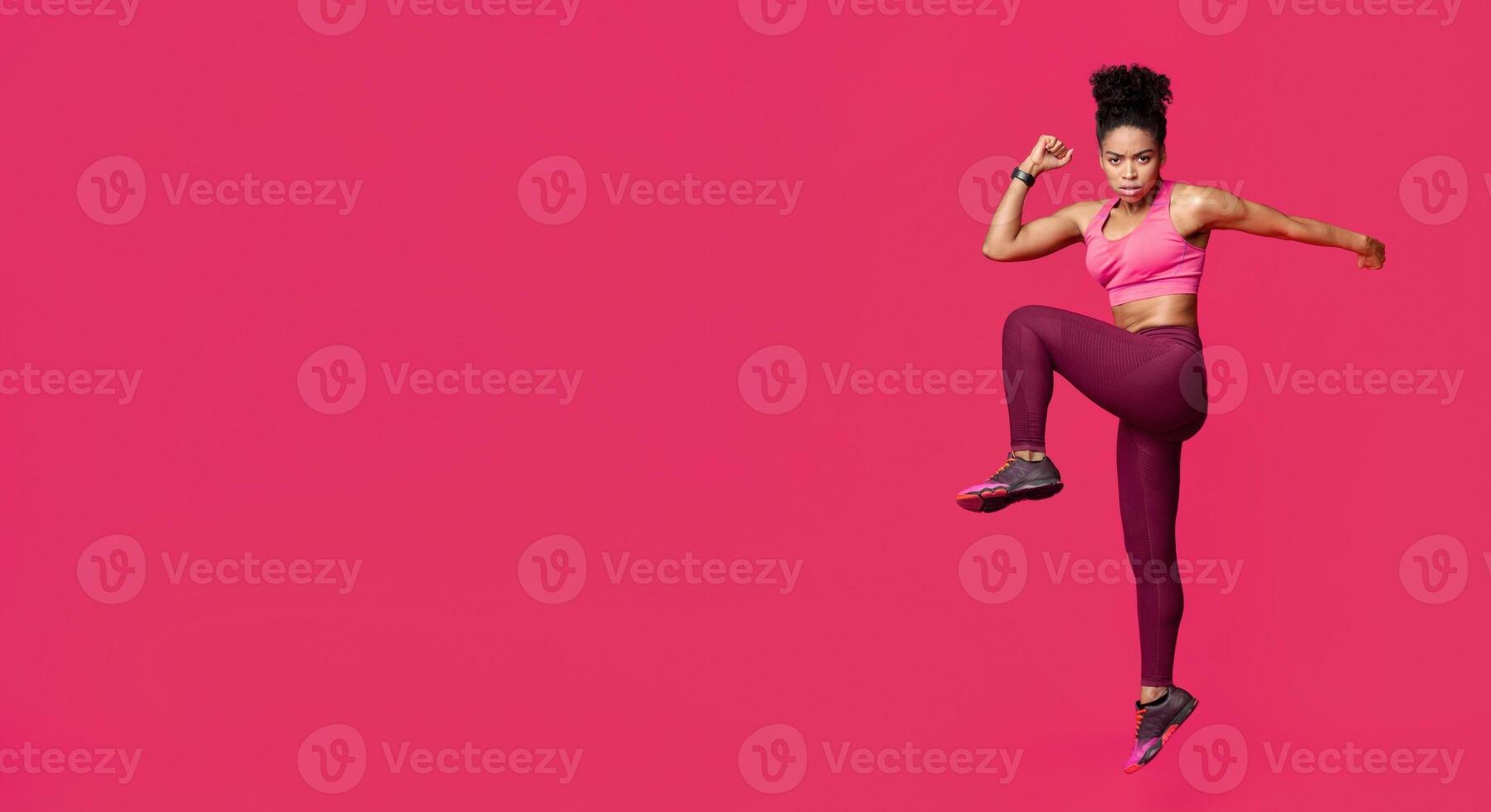 Active fitness afro girl making work out, warming up body before training, red background photo