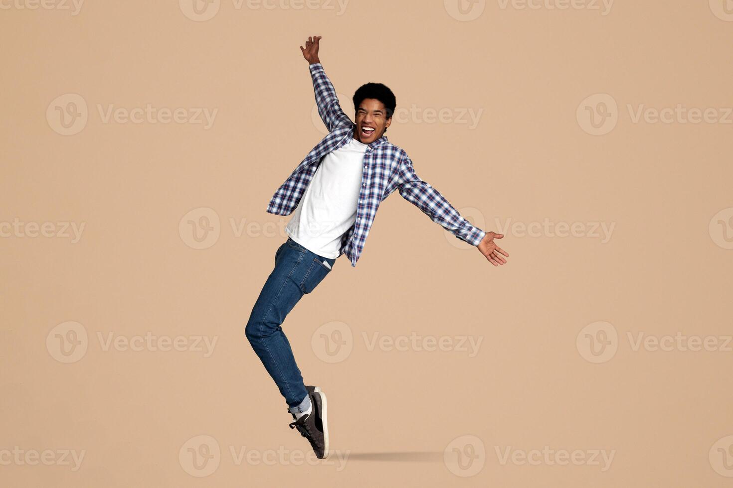 Funny Black Guy Fooling, Standing on Sneakers Toes on White Studio Background photo