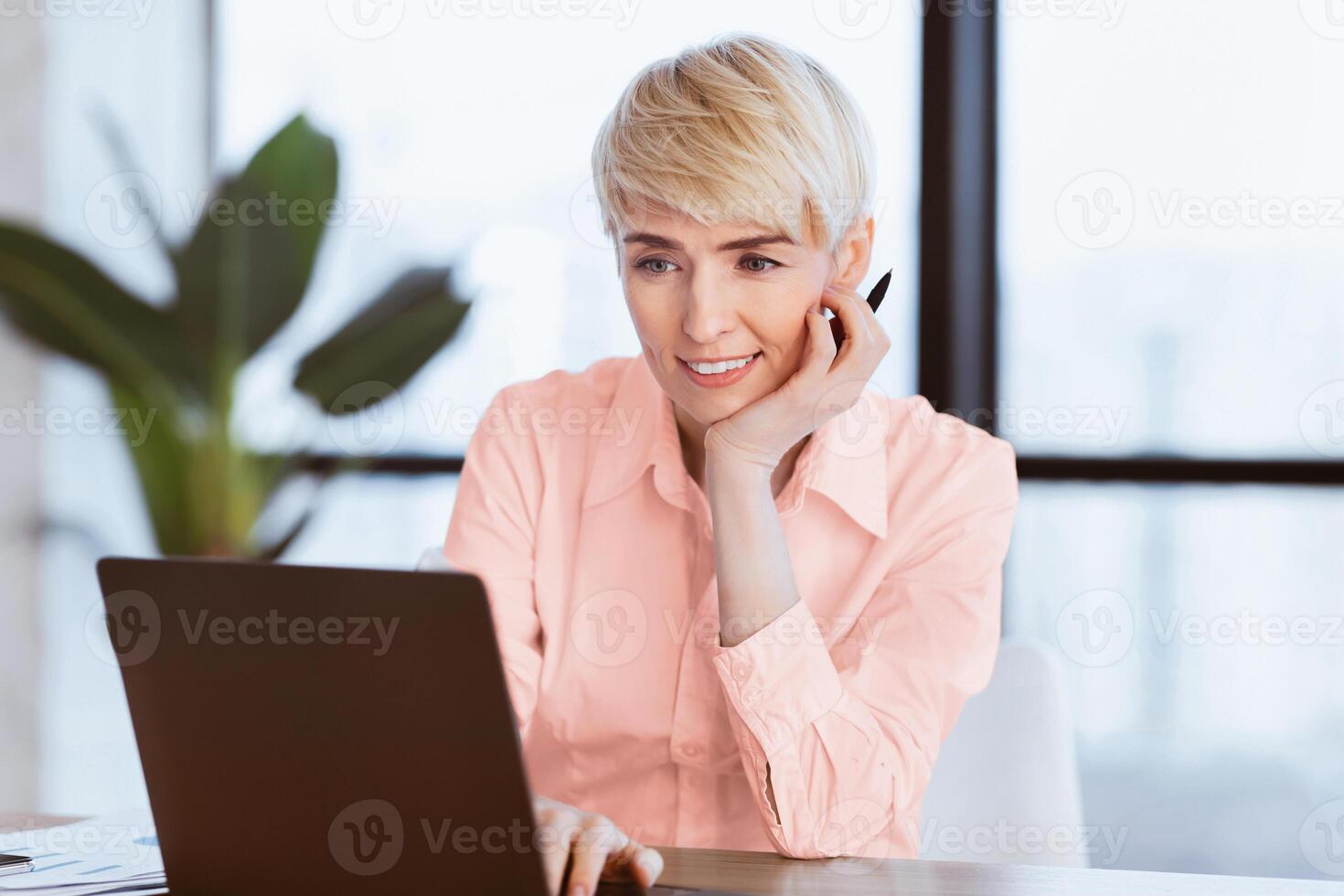 Smiling Mature Business Lady At Laptop Computer Working On A Project Sitting At Workplace In Office. Selective Focus photo