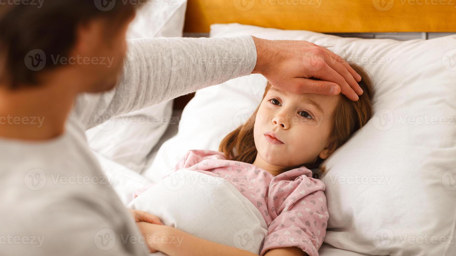 Man checking his ill little daughter temperature, touching his forehead, close up photo