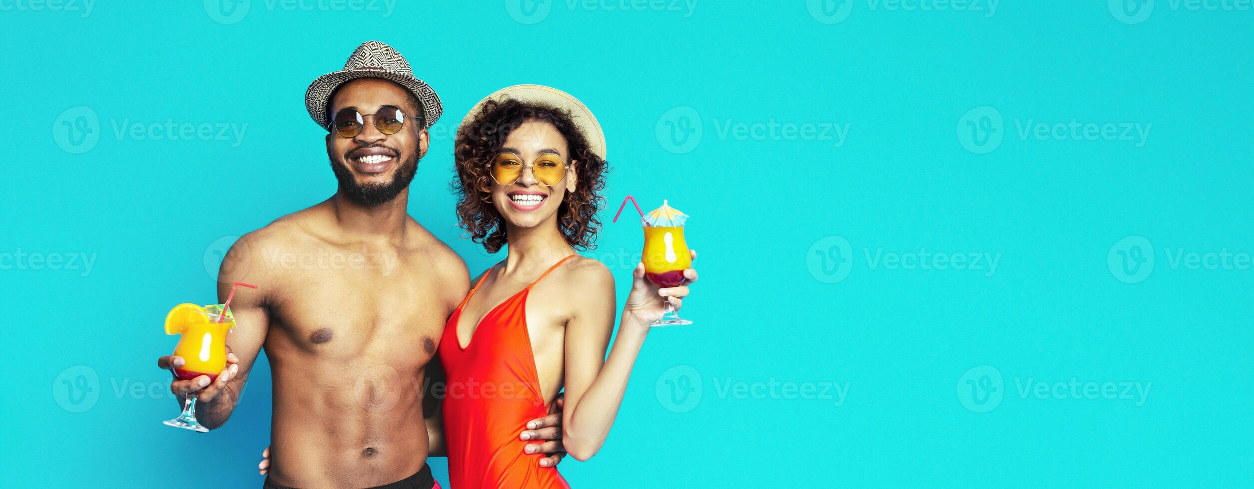 Black man and woman, dressed in summer attire and sunglasses, pose happily against a bright blue background, copy space photo