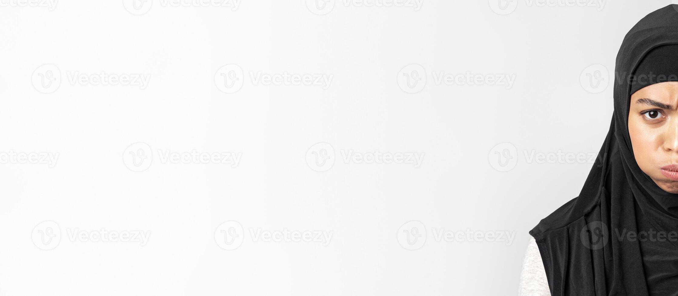 Offence. Closeup portrait of black muslim woman in hijab pouting, frowning and looking at camera, posing over grey background with empty space photo