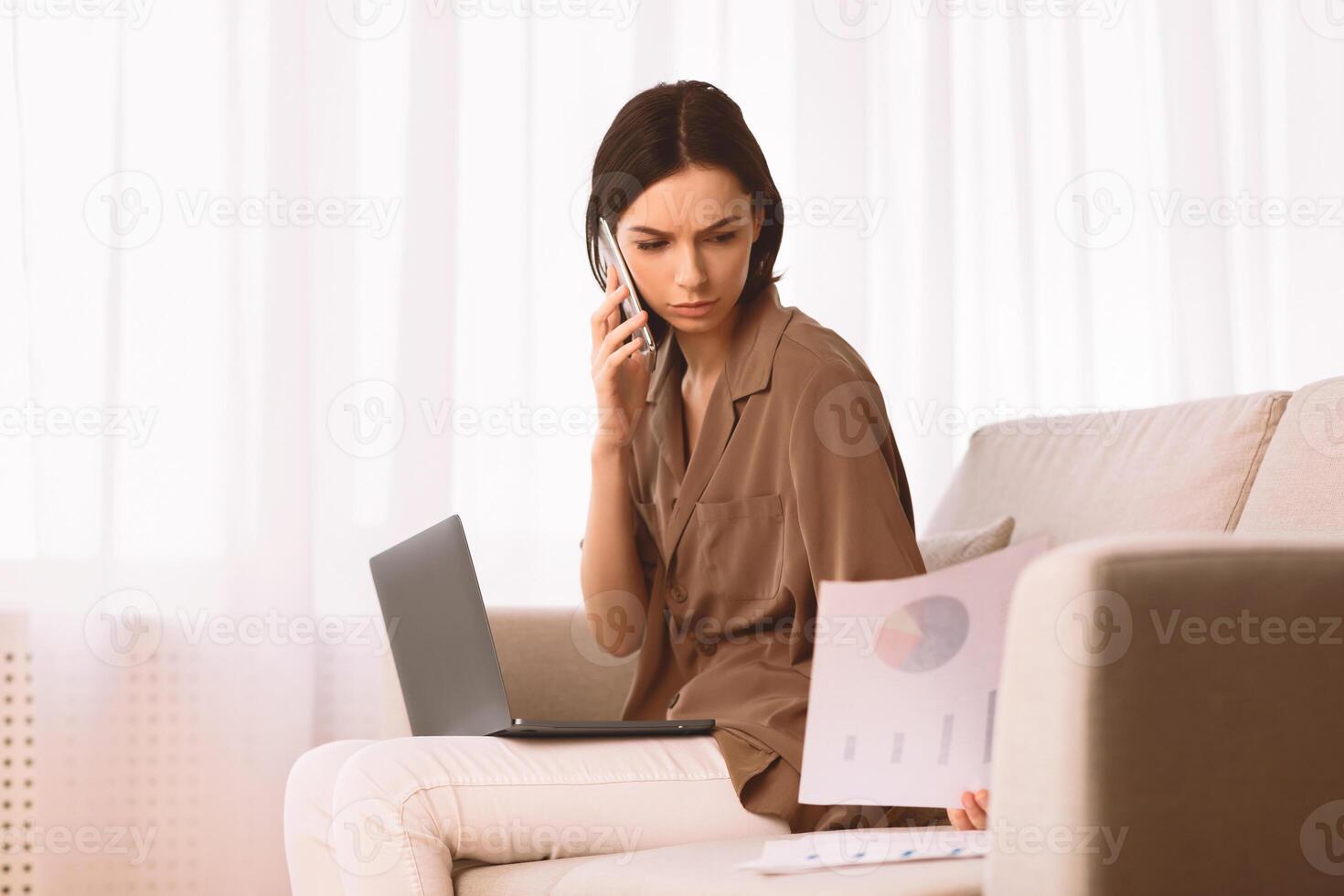 Discussing Document. Serious girl holding paper and talking on mobile phone, working at home office, copyspace photo
