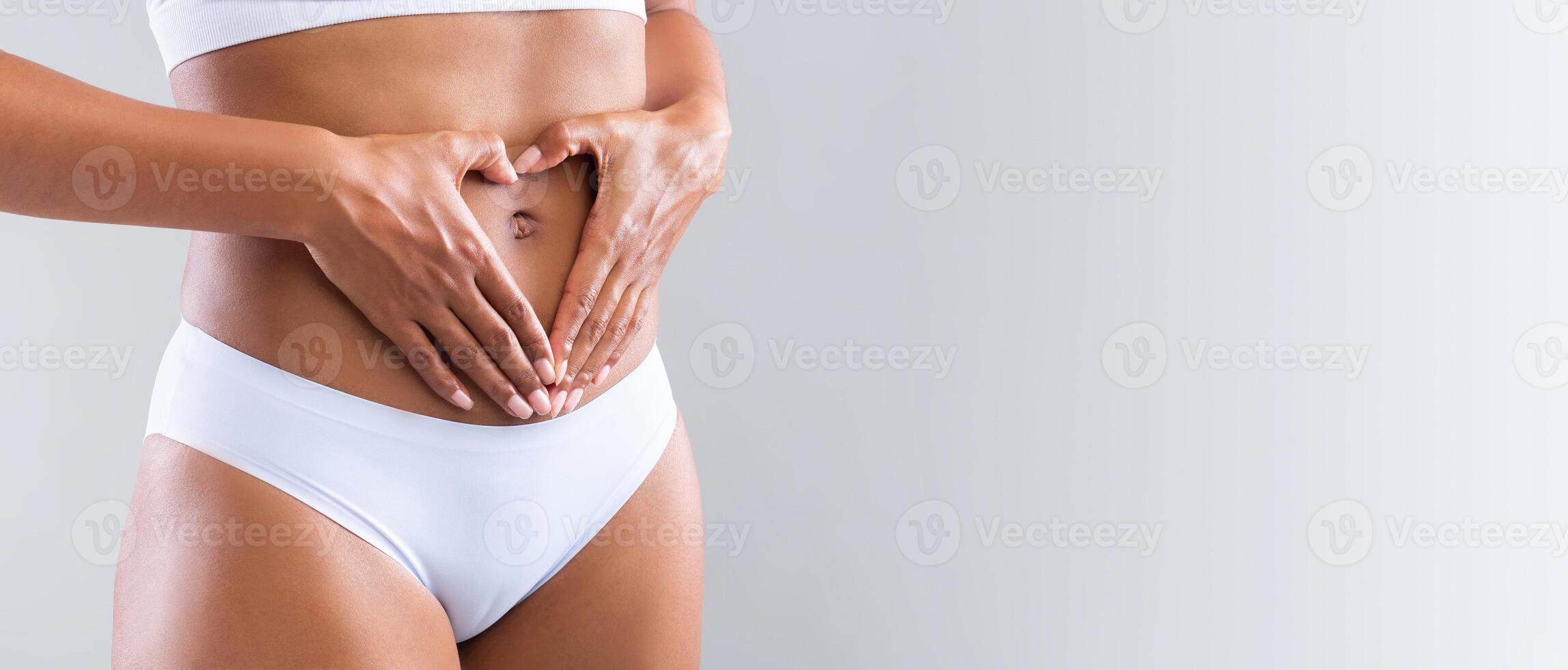 Prignant afro woman holding heart shaped hands against her small tummy, cropped, panorama with free space photo