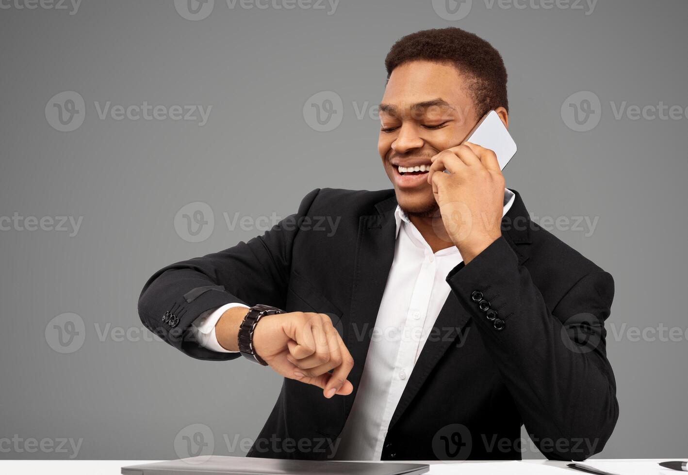 Time Is Money. Smiling black manager talking on mobile phone and looking at wrist watch, free space photo