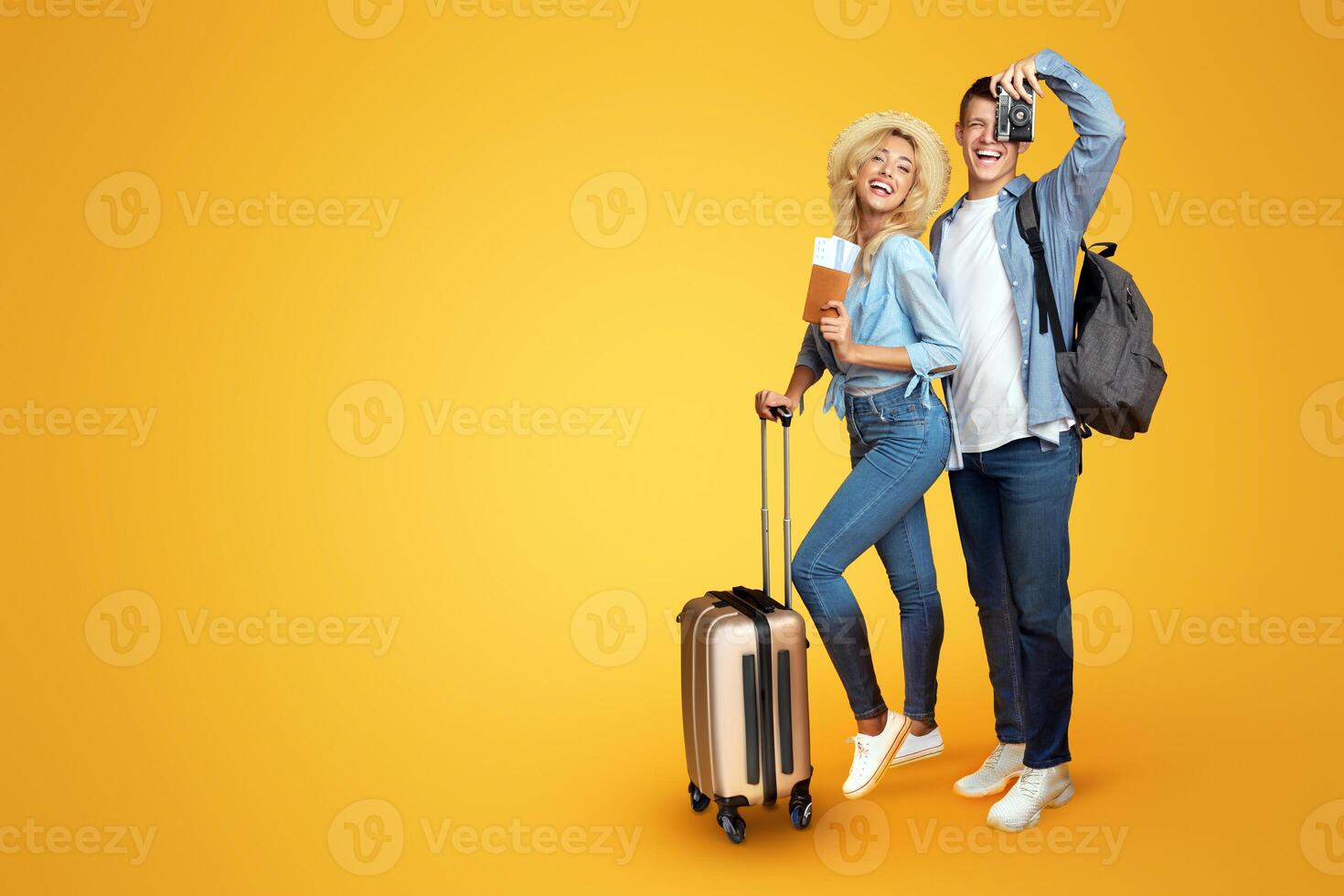Ready for vacation. Happy couple with suitcase and tickets over yellow background, copy space photo