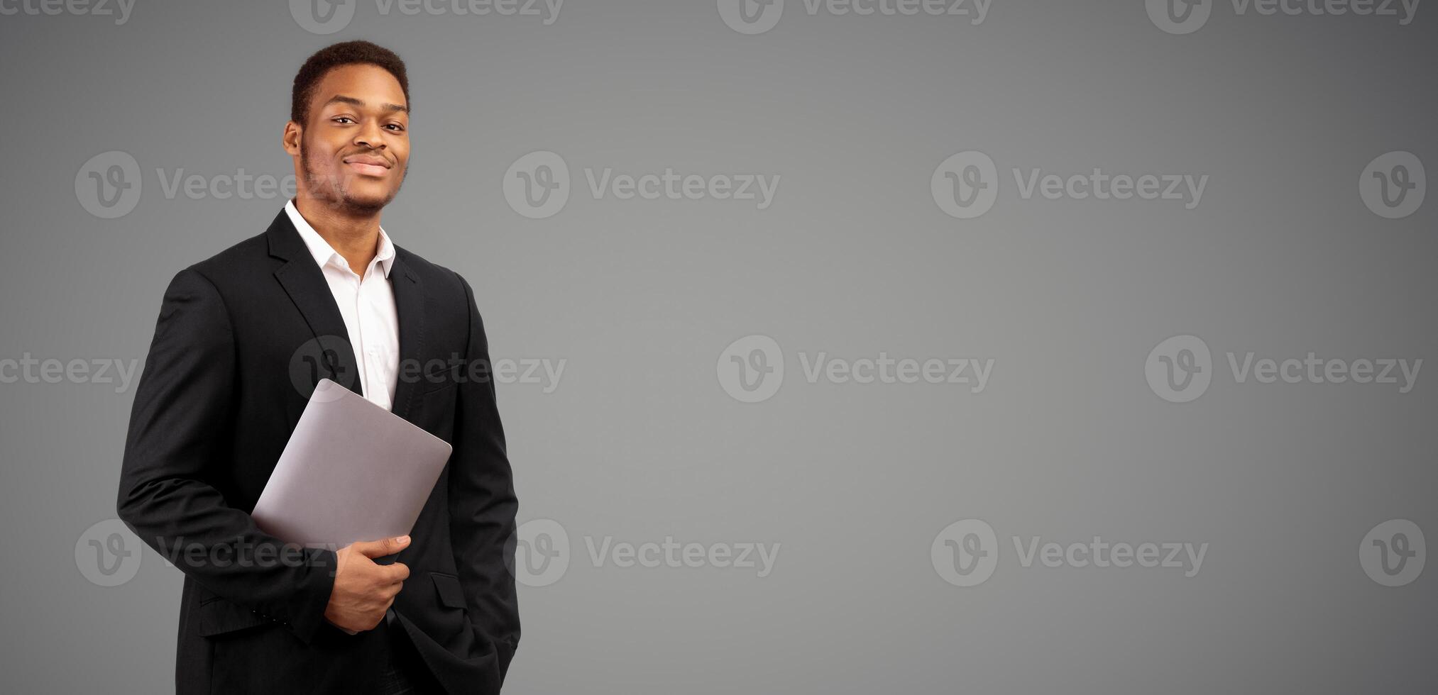 Confident Businessman. Black guy holding laptop looking at camera, isolated over white background, panorama, copyspace photo