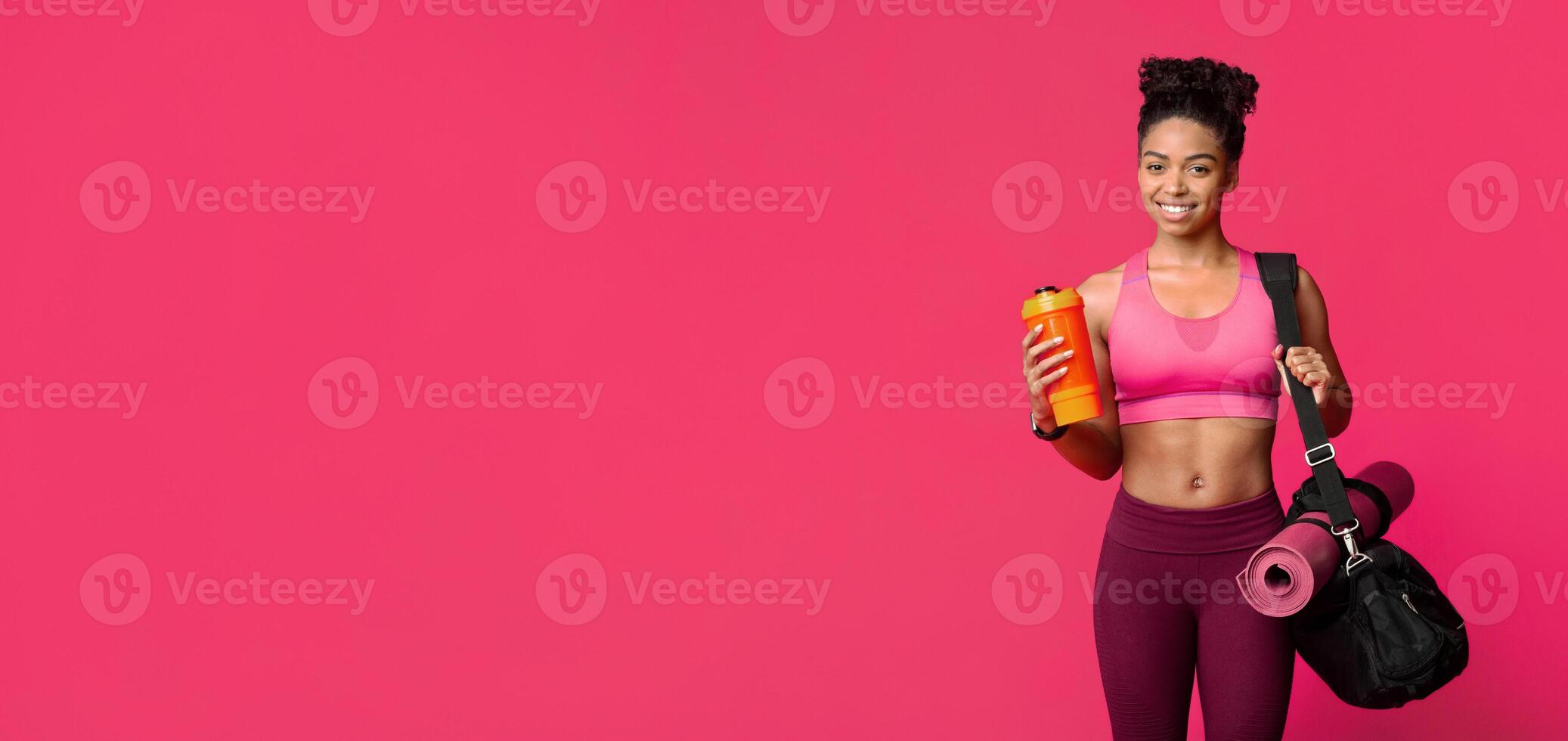 Portrait of happy fitness african girl with sporty bag, mat and shaker, enjoying healthy lifestyle photo