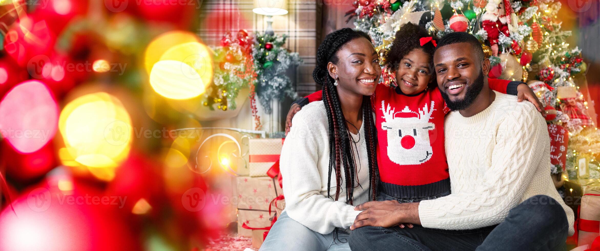Merry Christmas and happy New Year. Portrait of afro dad, mom and daughter posing near Xmas tree at home photo