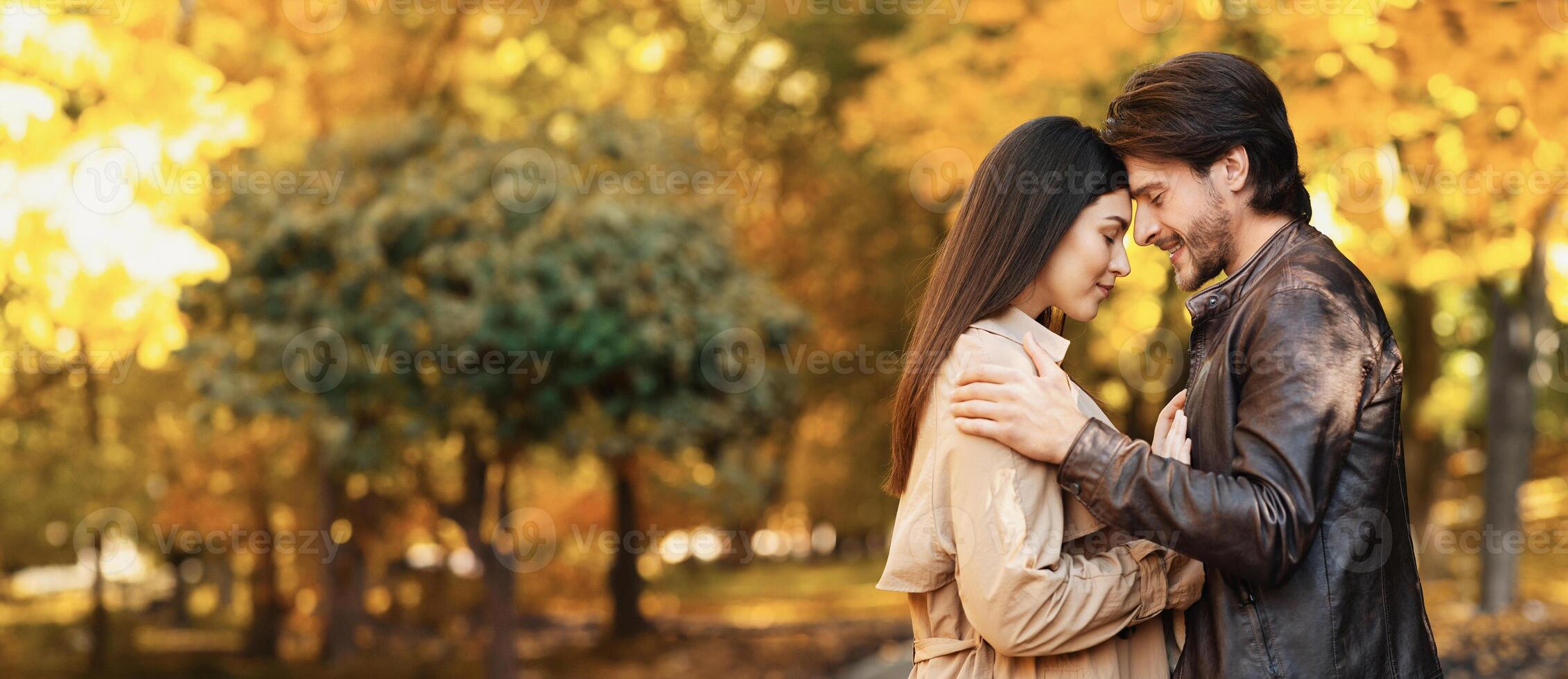 Couple in love embracing and touching each other with foreheads in autumn park photo