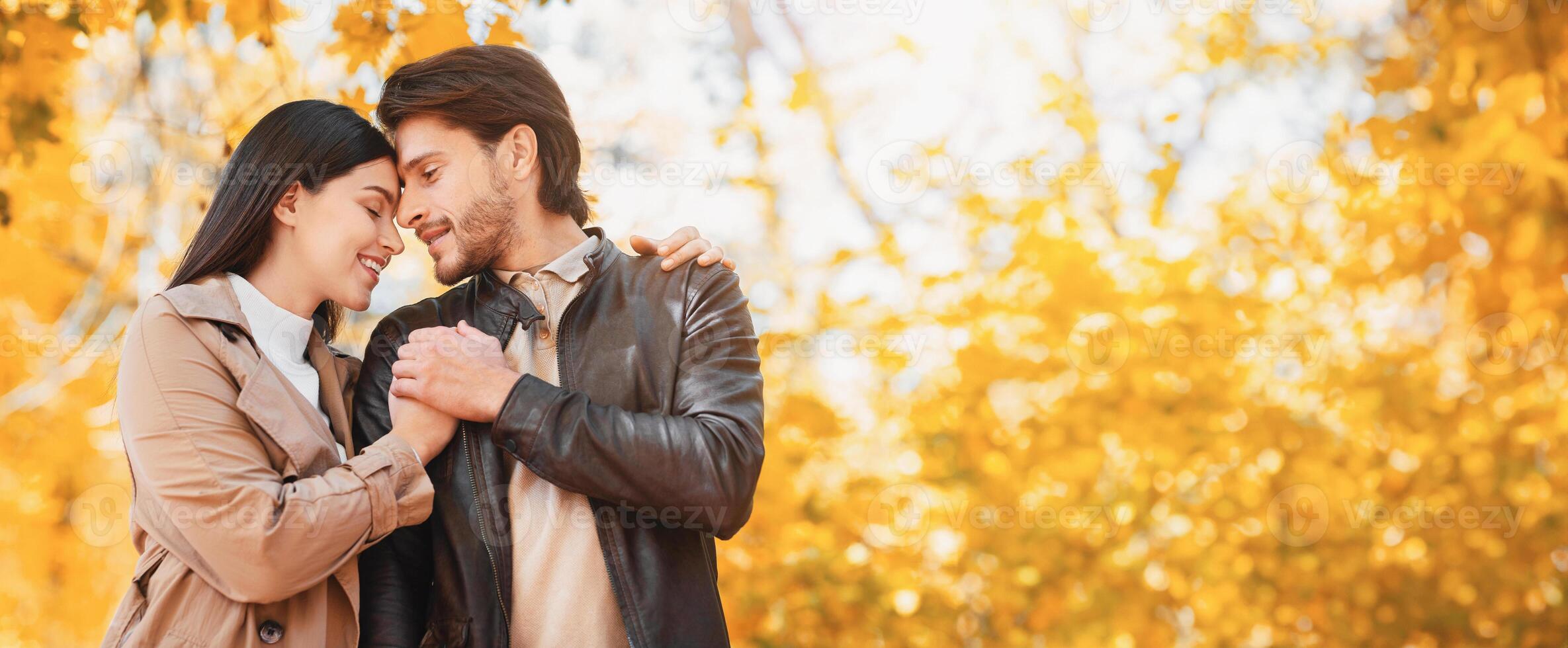 Emotional young lovers cuddling during romantic date at autumn forest, copy space photo