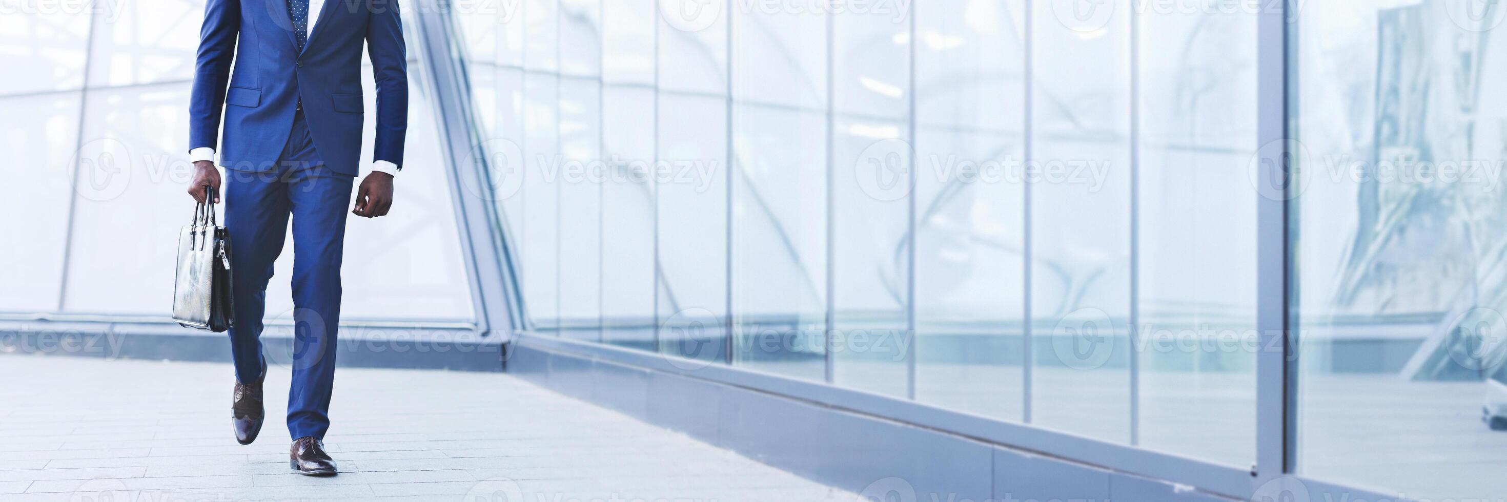 Successful Business Manager. Unrecognizable African American Guy Holding Briefcase Walking Against Modern Building. Cropped, Panorama With Copy Space photo