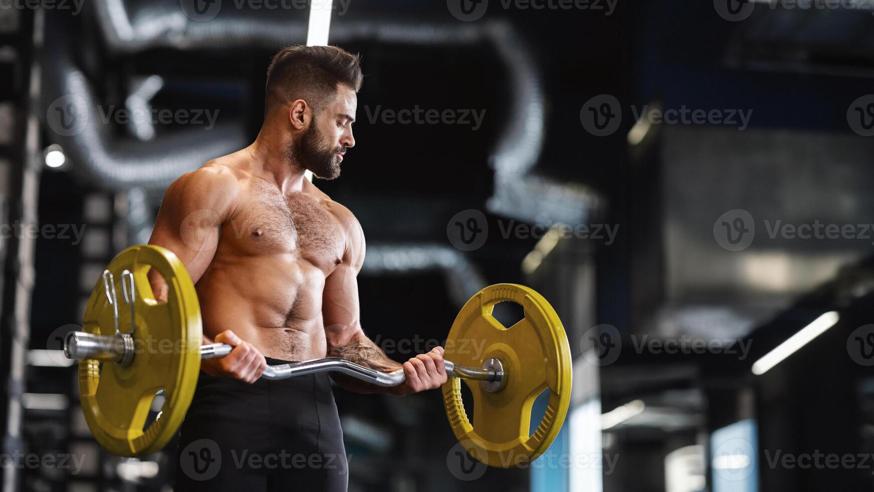 Handsome naked weightlifter lifting heavy barbell in gym, free space photo