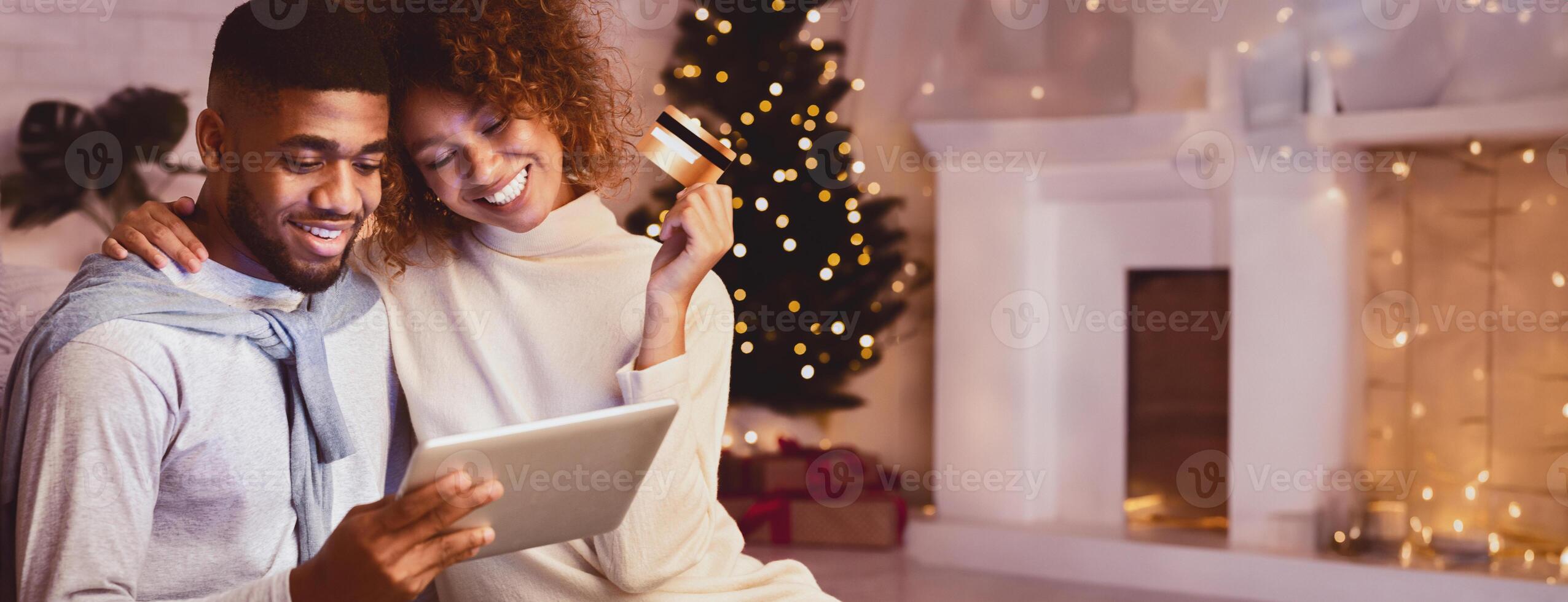 Christmas holiday. African-american couple choosing gifts on tablet, using credit card photo