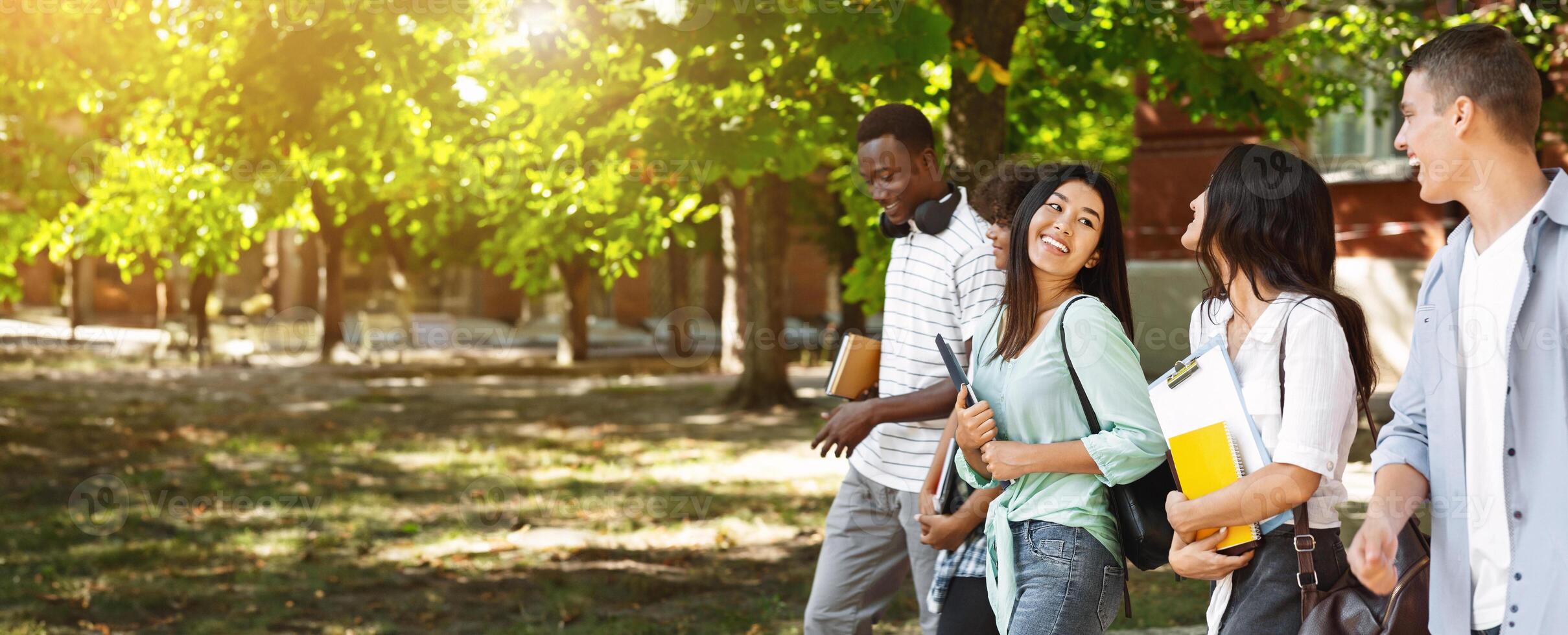 Joyful Multi-Ethnic College Friends Walking Outdoors After Classes And Chatting, Free Space photo