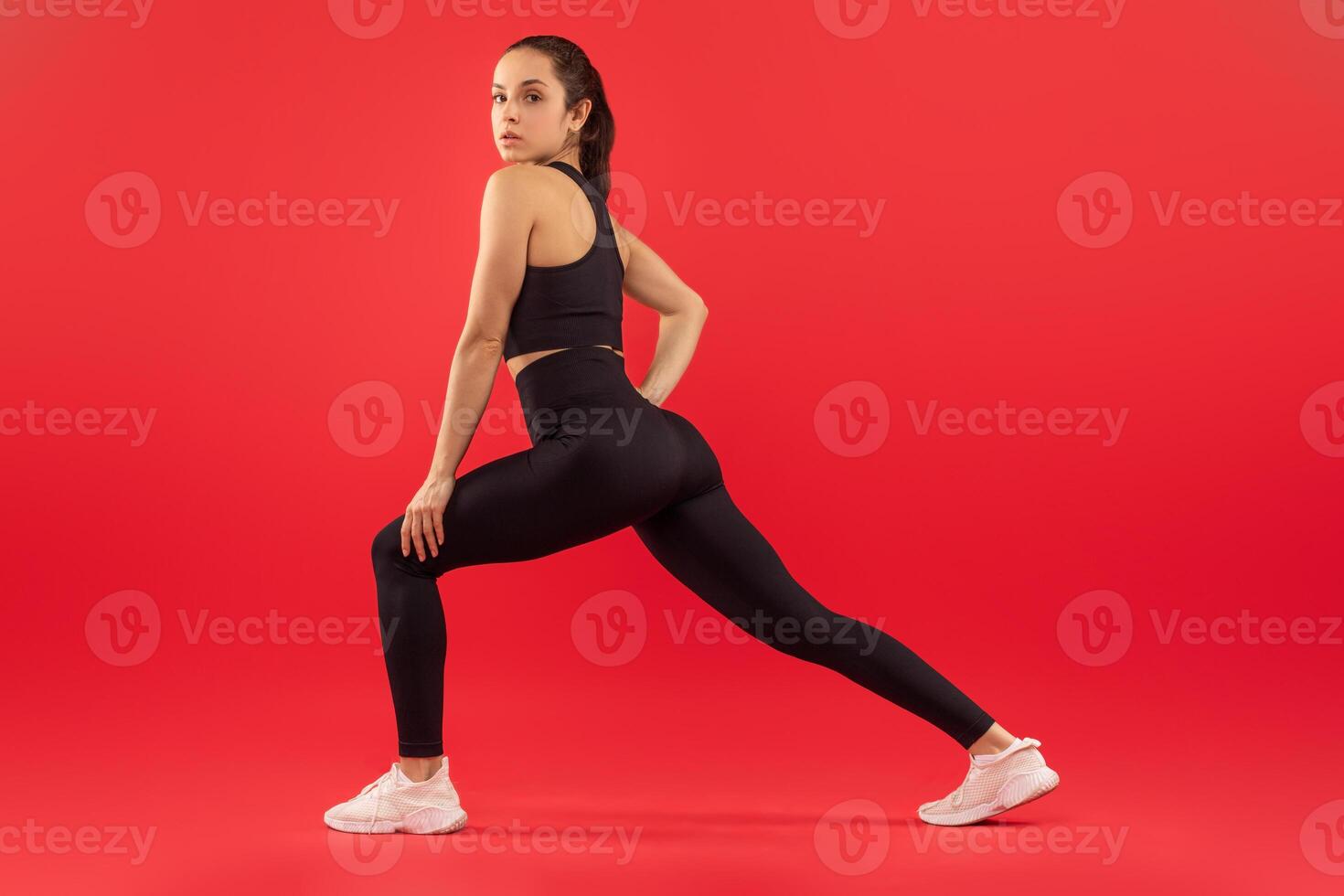 A woman wearing a black sports bra top and leggings is shown. She appears to be engaged in physical exercise or fitness activities, showcasing her athletic attire and physique. photo