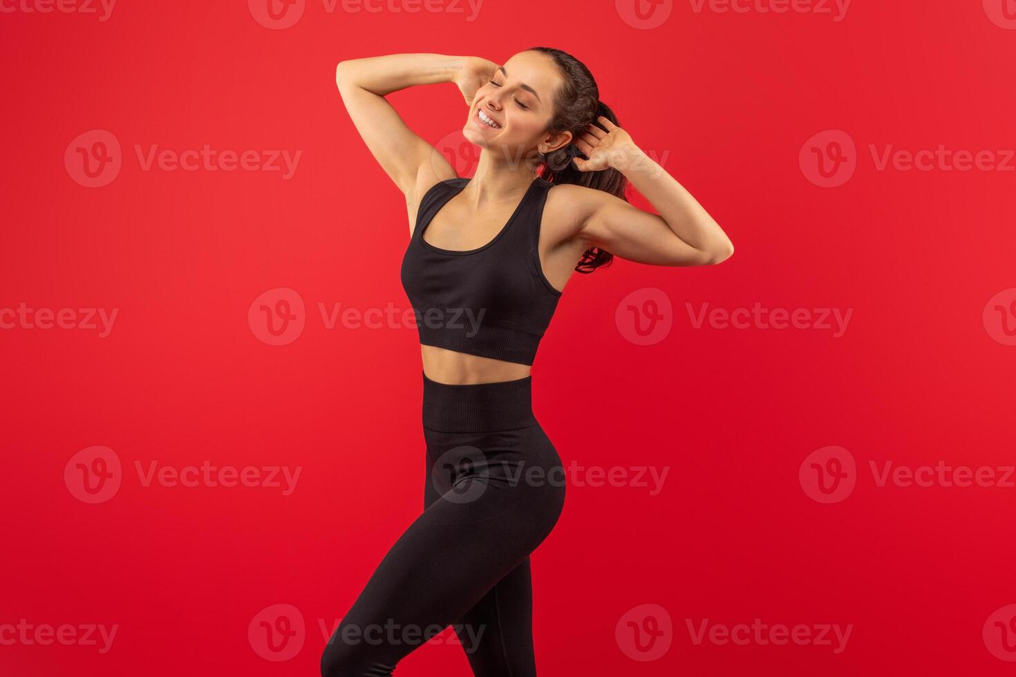 A woman is shown wearing a black sports bra top and matching leggings. She appears to be engaged in physical exercise or fitness activities, showcasing strength and determination in her outfit. photo