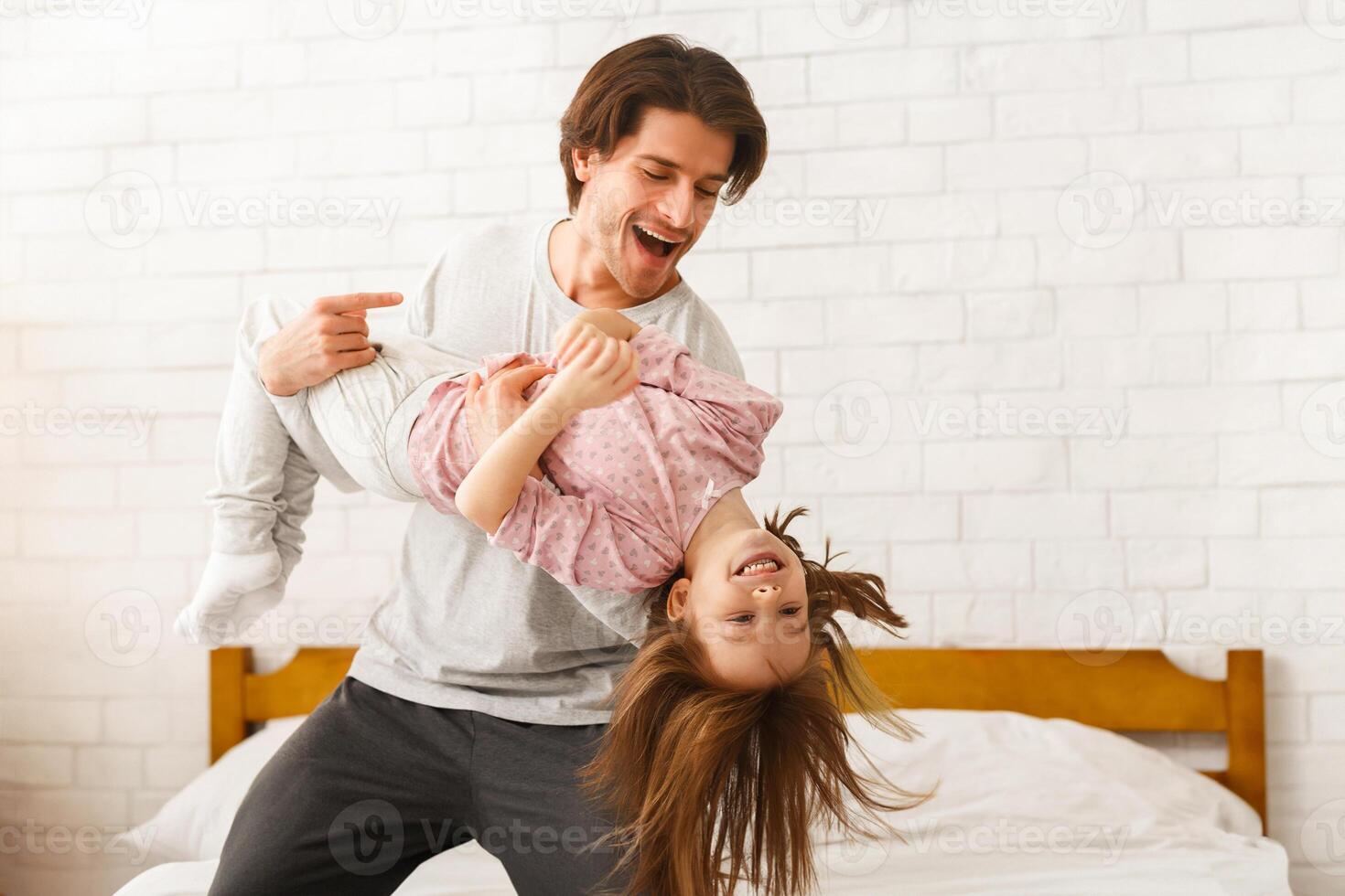 Young handsome father playing with his preschool daughter at home in morning, copy space photo