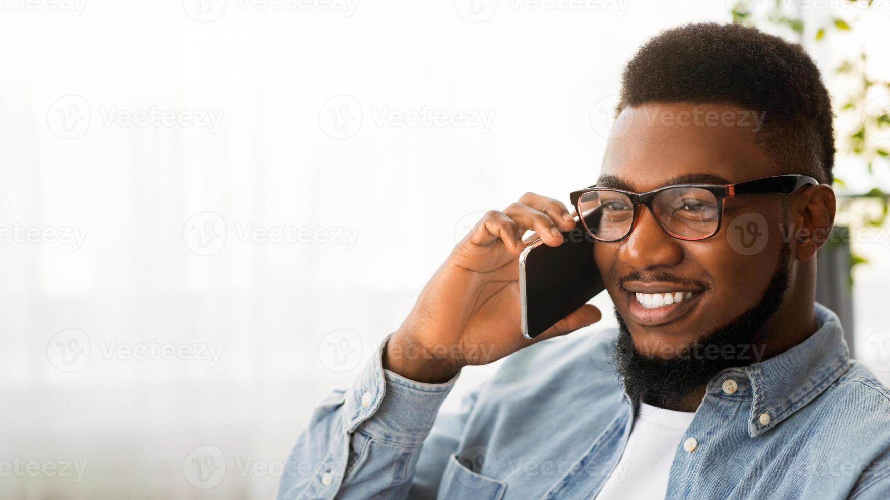 In touch. Handsome african american man in glasses talking on cellphone with somebody, copy space photo