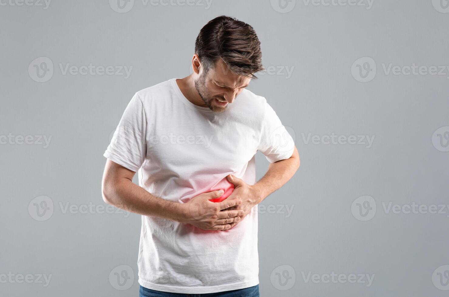 Middle-aged man holding his lightened with red right side, suffering from liver pain, grey studio background, copy space. Sad man having cirrhosis, rubbing his right side. Liver diseases concept photo