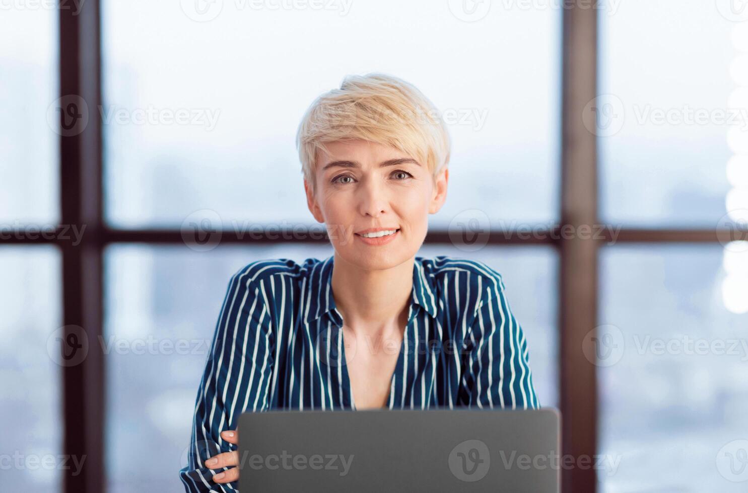 Businesswoman's Portrait. Mature Business Lady Sitting At Laptop Smiling To Camera In Modern Office. Selective Focus photo