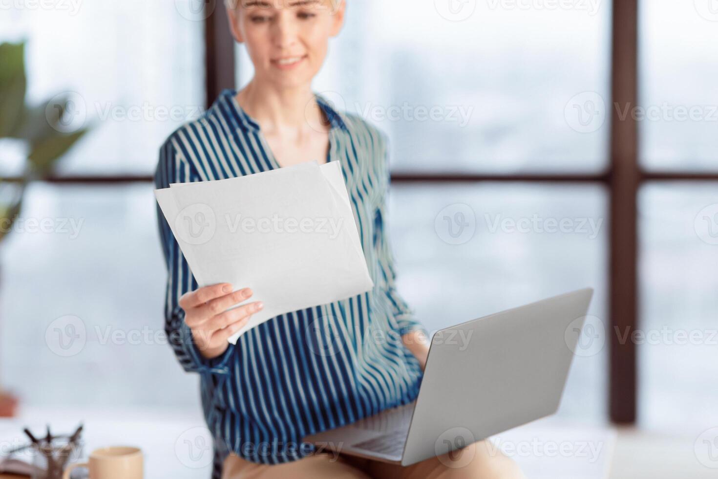 Business Accounting. Businesswoman Holding Laptop And Documents Sitting On Table In Modern Office. Selective Focus, Shallow Depth photo