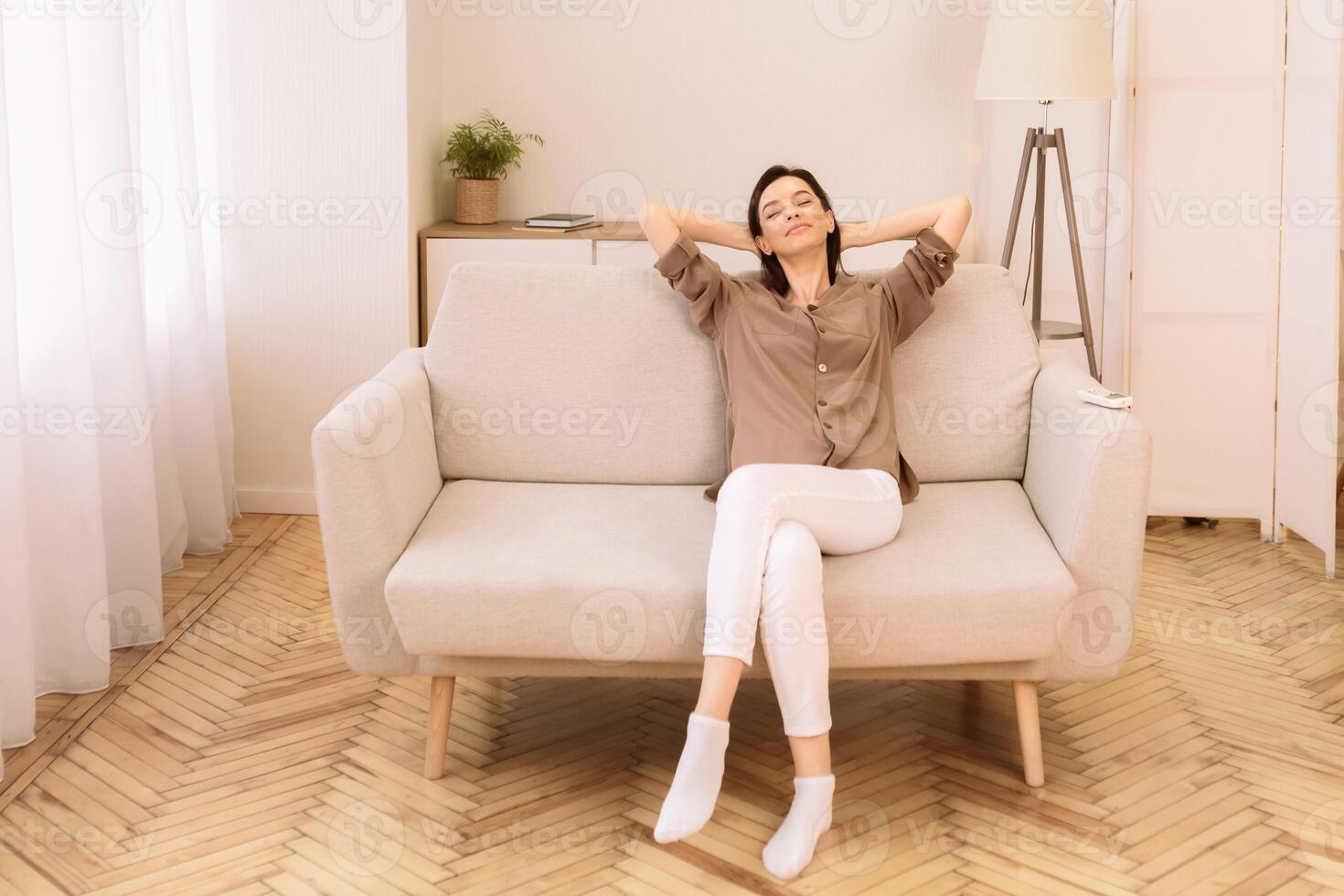 Weekend. Relaxed calm woman resting at home on sofa, satisfied young lady stretching on couch, leaning back, copyspace photo