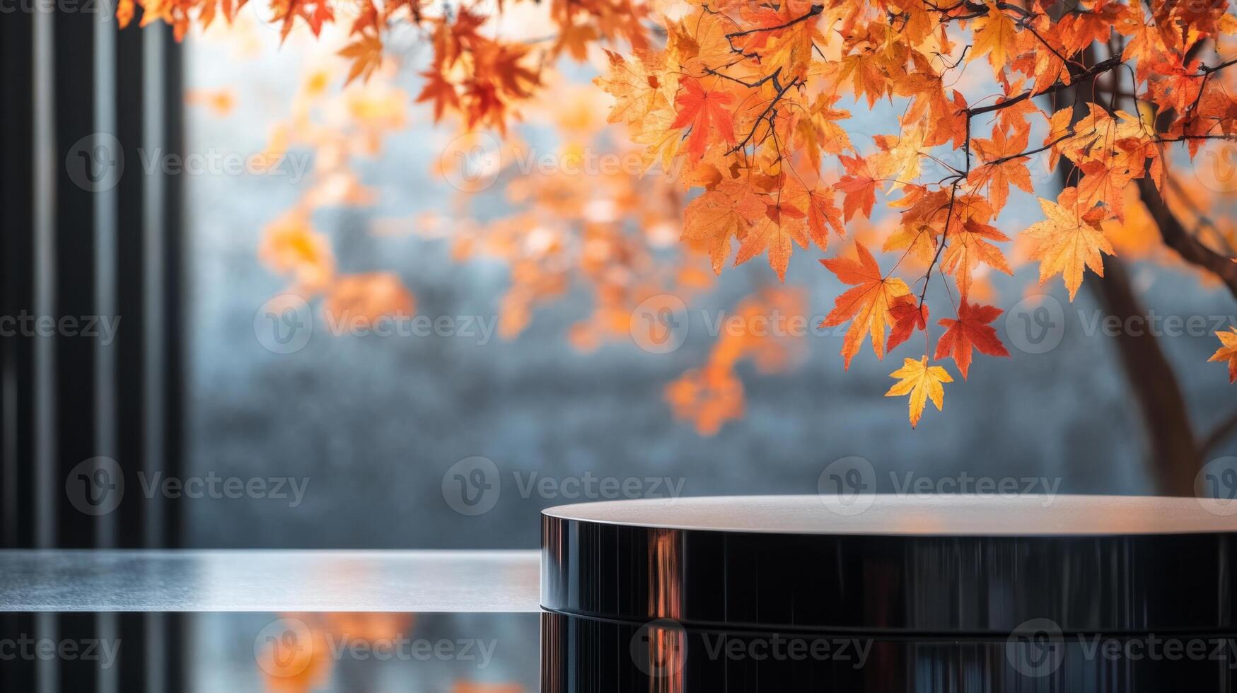 A round black podium sits on a glossy black surface. The podium is positioned in front of a large window with fall leaves. The leaves are orange and yellow, and they are out of focus. photo