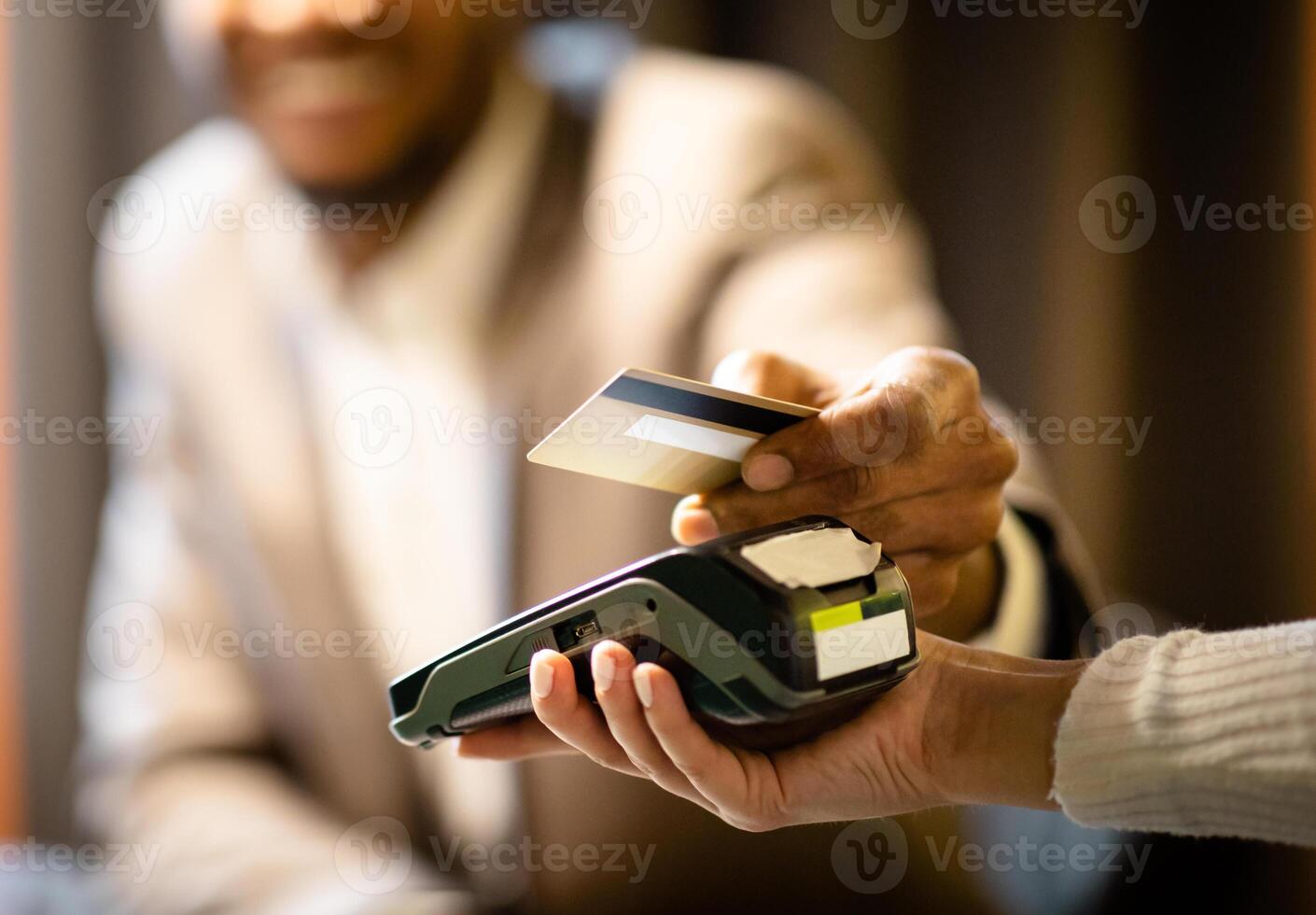 NFC Technology. Close up of black manager smiling, giving credit card to waitress paying with gold credit card in cafe photo