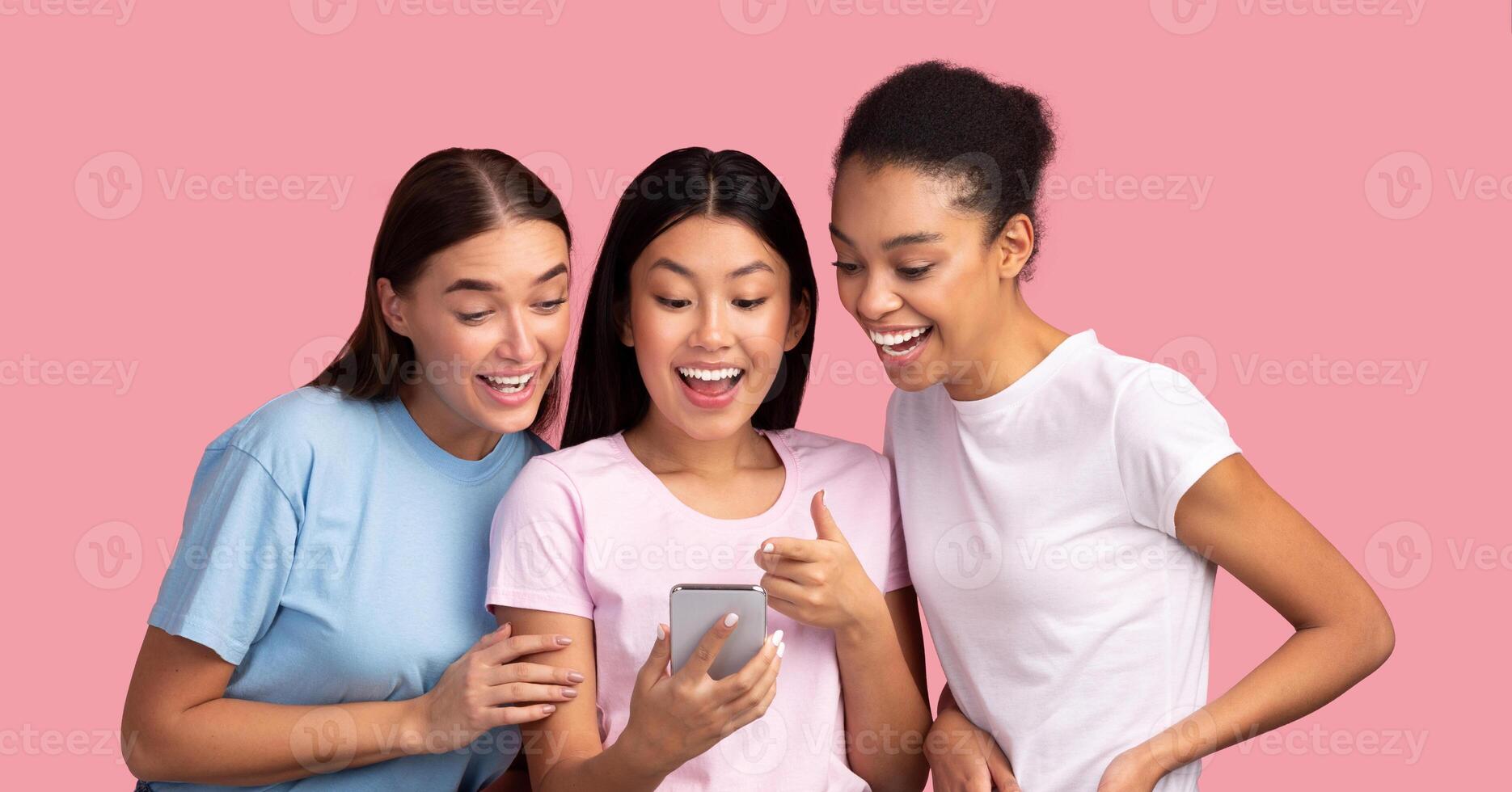 Cool App. Three Millennial Girls Using Smartphone Showing And Recommending Mobile Application To Friends Standing Over Pink Background photo
