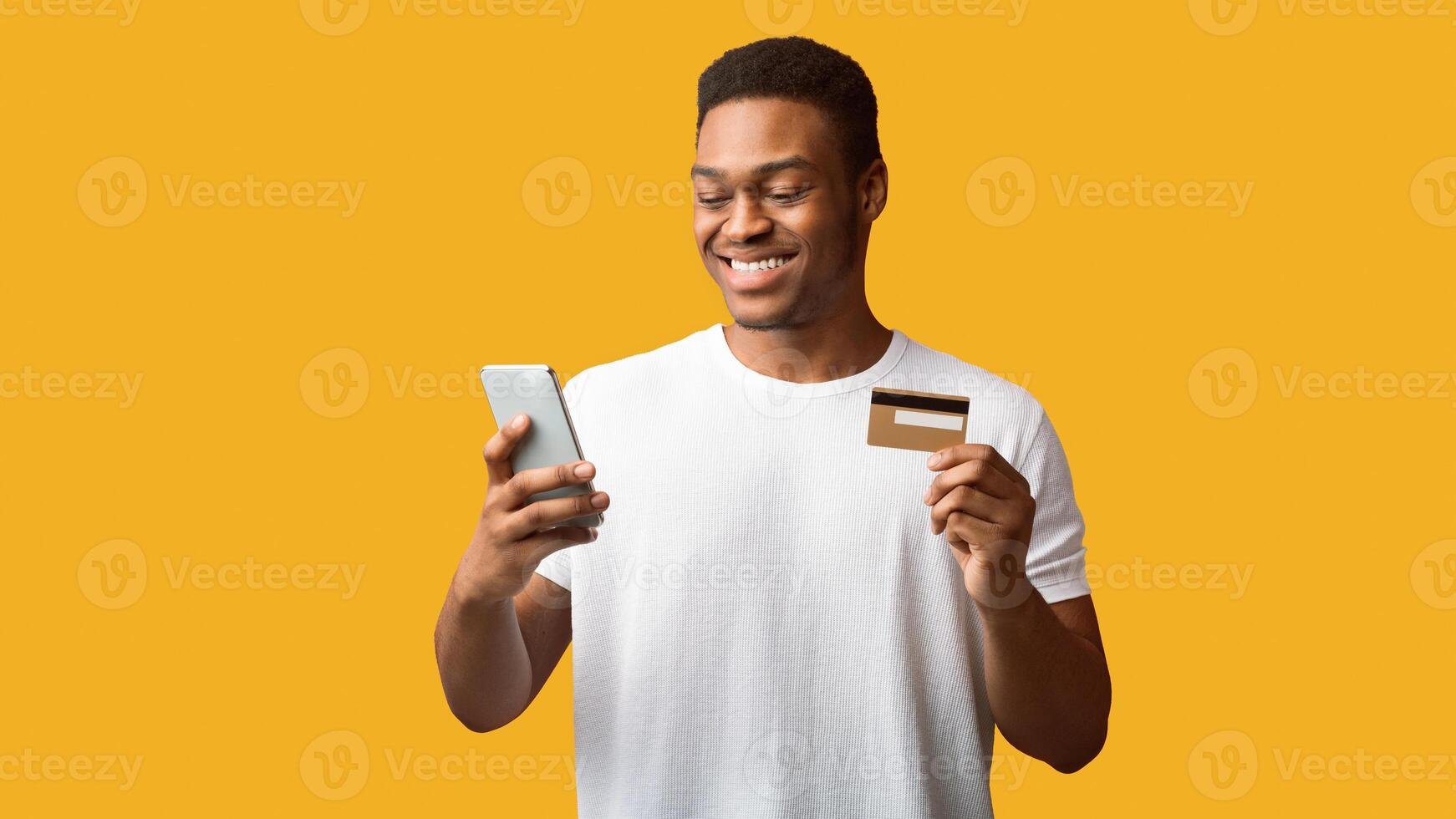 Online Store. African american man holding credit card and smartphone, ready to buy something. Copy space photo