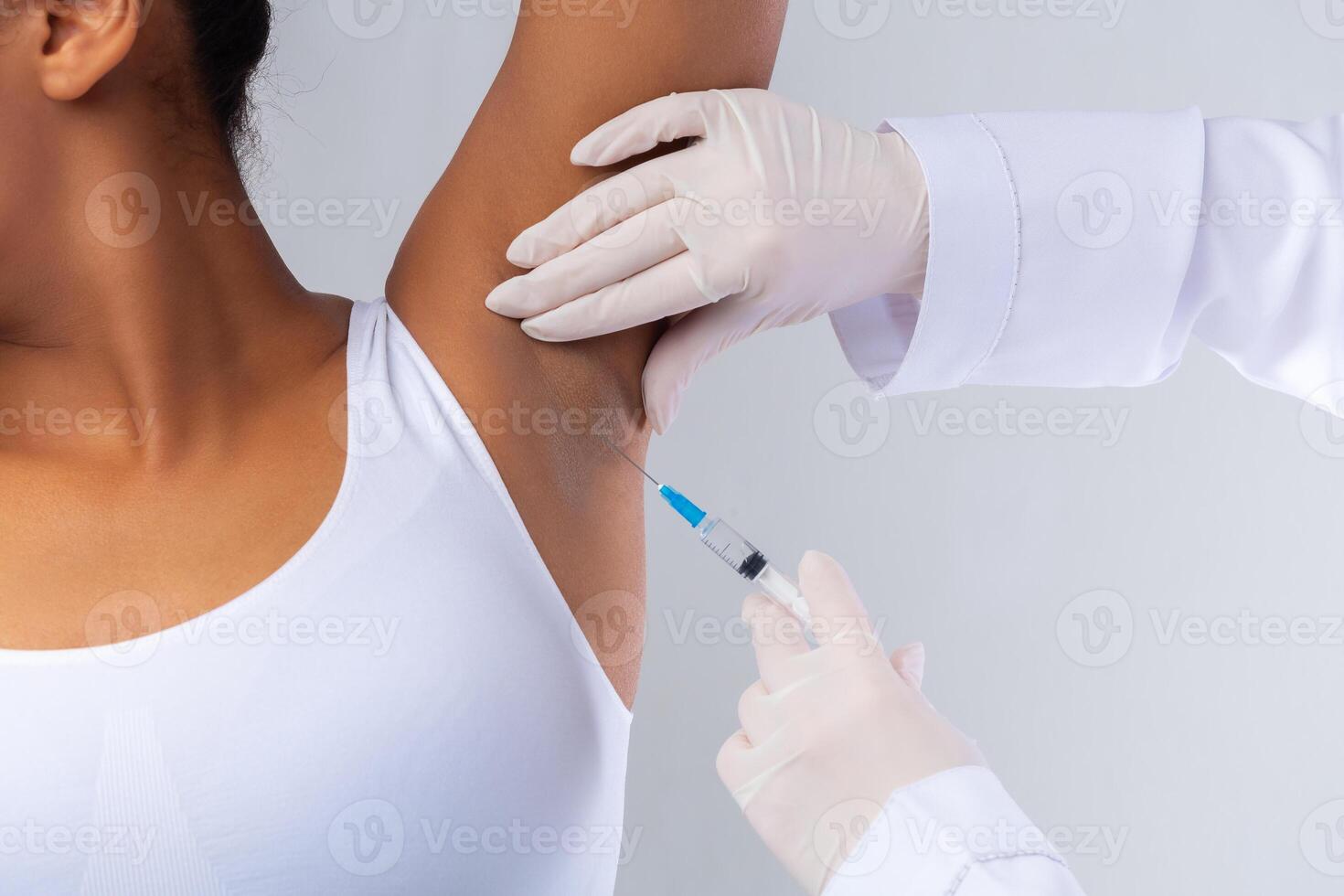 Doctor makes intramuscular injections of botulinum toxin in underarm area against hyperhidrosis, cropped, armpit of black woman photo