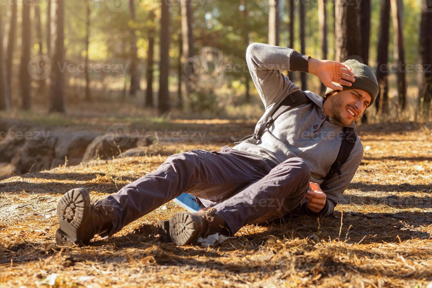 Young man having trouble feeling knee pain during travel in forest. Health problem in journey, copy space photo