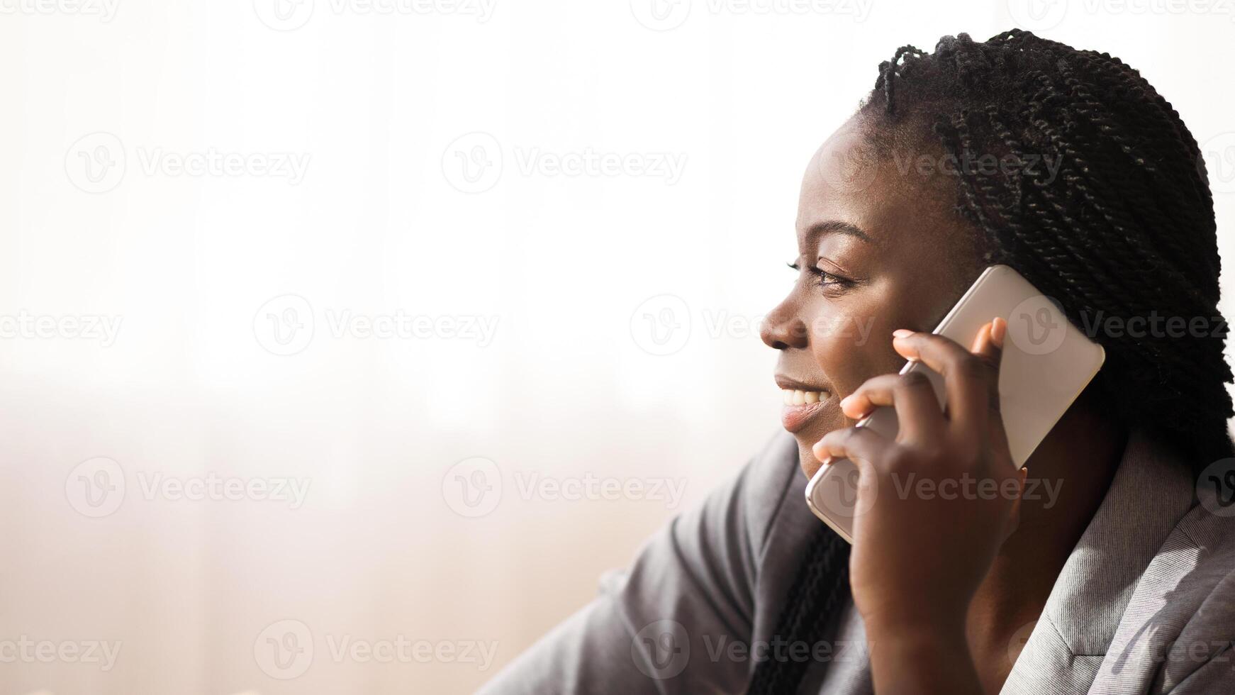 In touch. Profile portrait of smiling african american woman talking on cellphone with somebody against window background, copy space photo