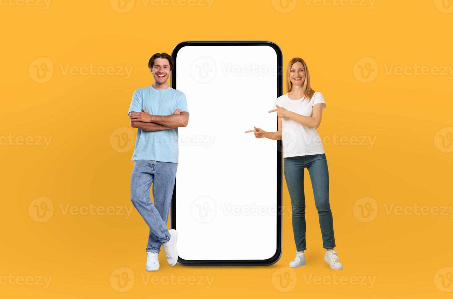 Young couple smiles are infectious as they stand side by side, presenting a large smartphone with a pristine, empty screen, ready to capture the imagination. photo