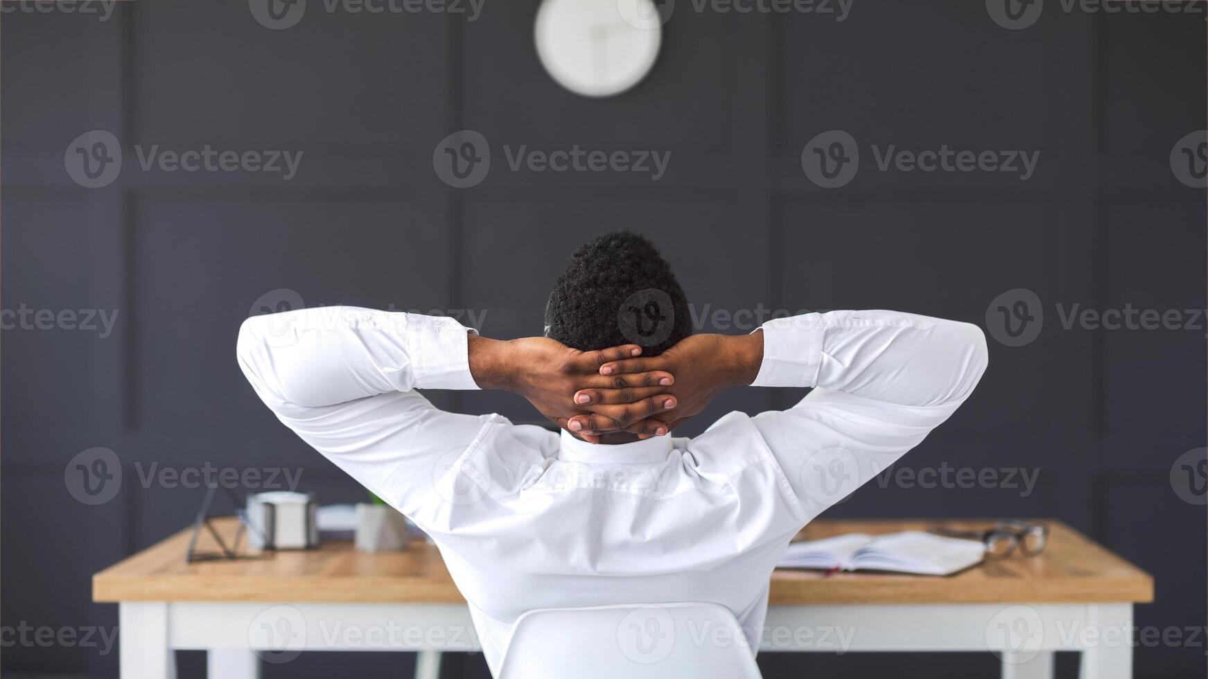 Back view of black employee relaxing in office, having break, copy space photo