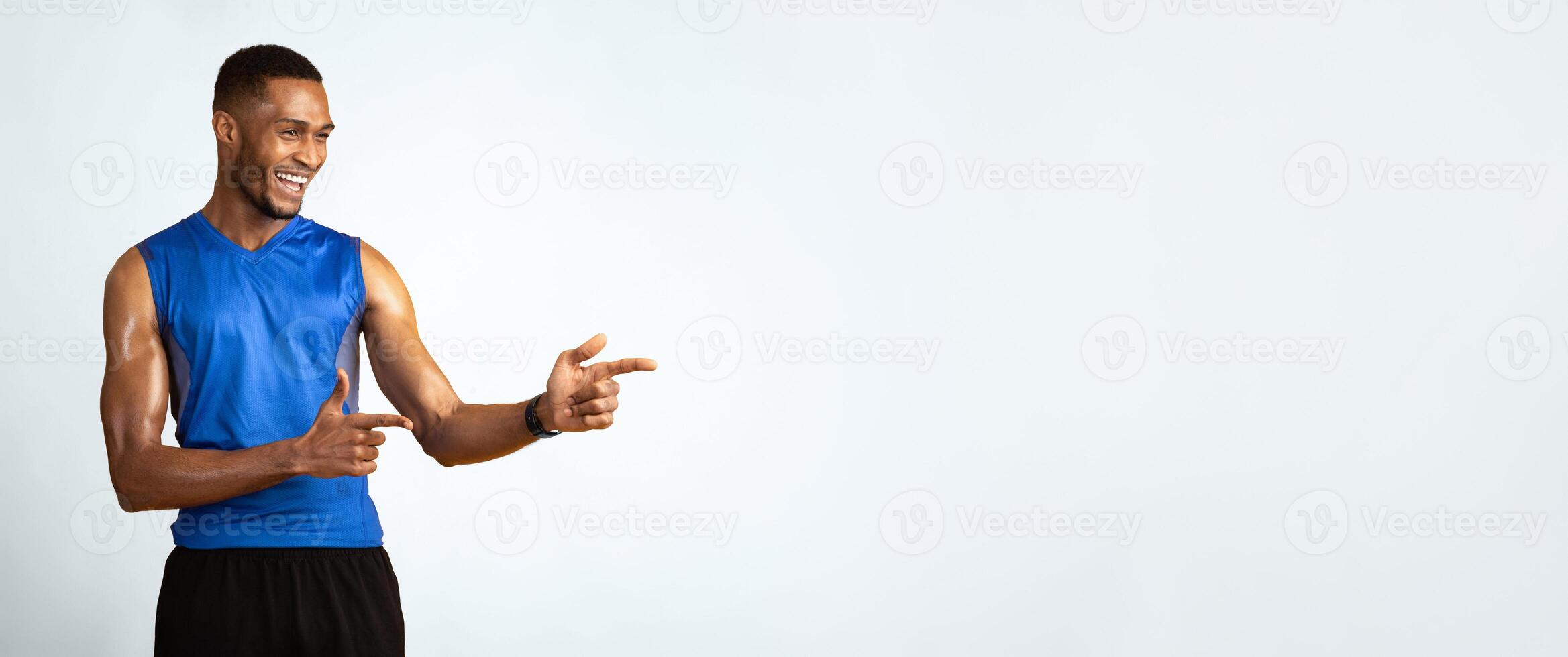 Great Promo. Happy black sportive guy pointing two index fingers aside at copy space over yellow studio background photo