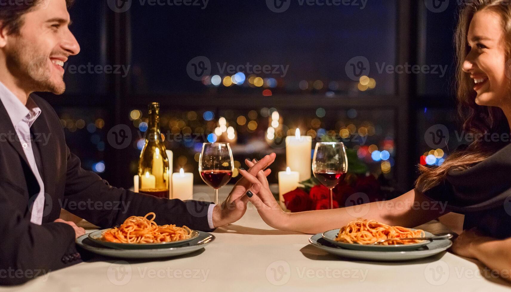 Romantic couple touching hands and smiling while having dating in restaurant. Happy evening together concept photo