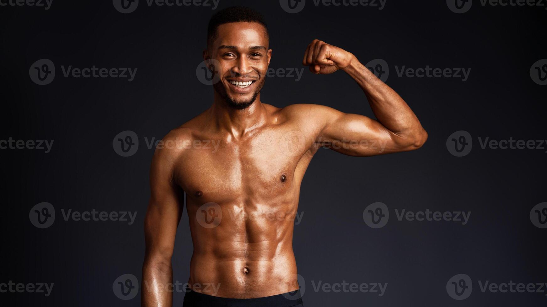 Athletic Man's Torso. Happy afro fitness model showing shoulder muscles, strong hands, chest and biceps over black wall photo