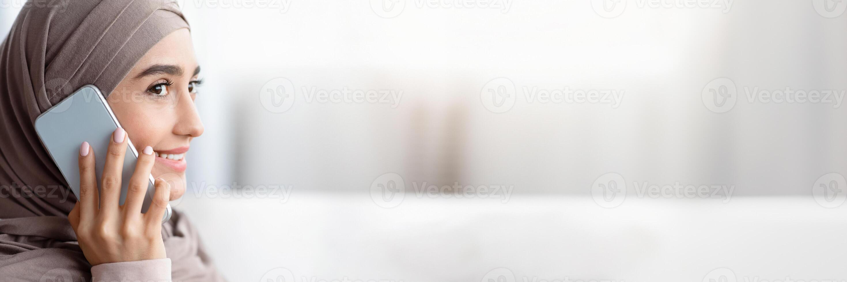 Modern Communication. Closeup Portrait Of Muslim Woman Talking On Cellphone And Looking Away, Side View With Copy Space photo