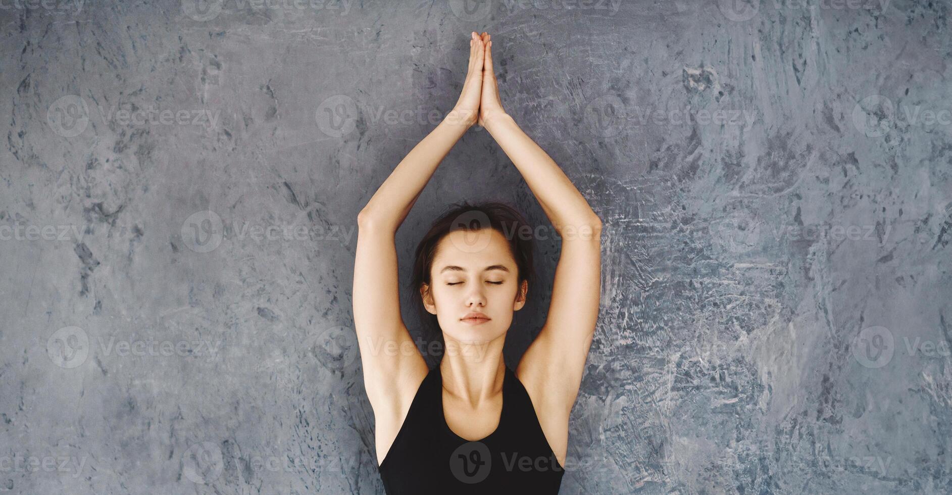 A woman dressed in a black top is practicing yoga poses in a room. She is focused and performing various stretches and poses on a yoga mat. photo