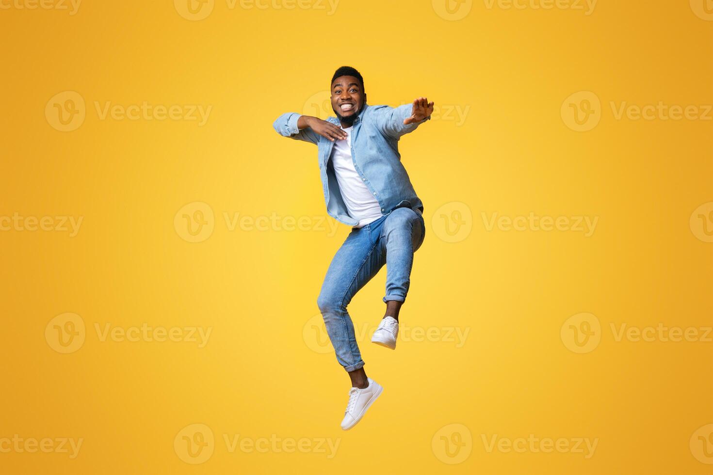 Fight with your diffidence. Funny african american guy jumping and making karate moves on yellow background with free space photo
