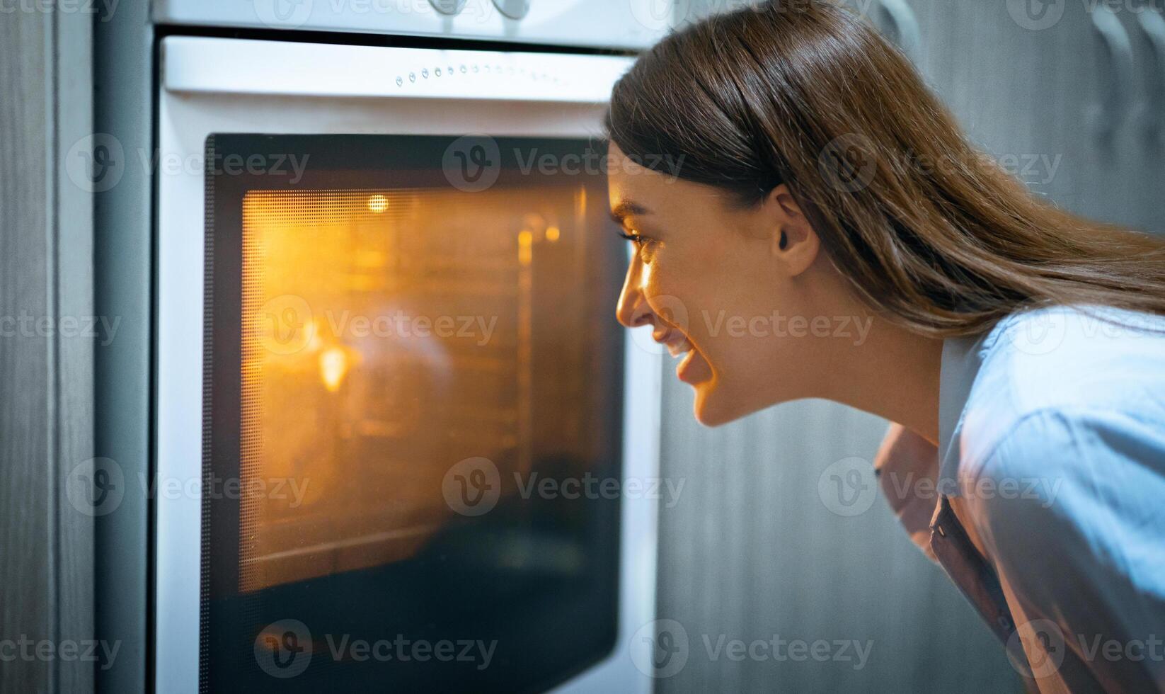 Stay at home. Happy woman looking into oven showcase at cooking lunch, free space photo